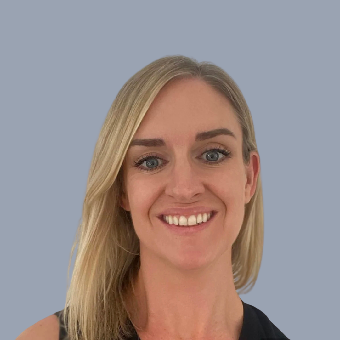 A woman with blonde hair and blue eyes smiling, wearing a black sleeveless top, against a plain light blue background.