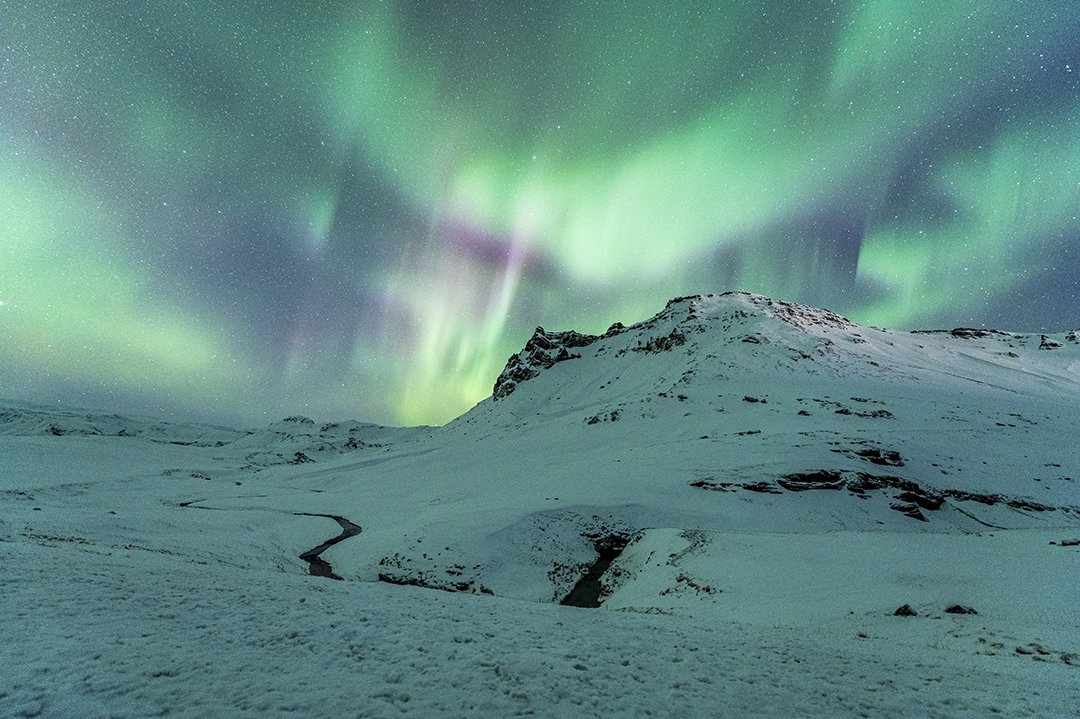 Iceland maountain in the winter with the northern lights dancing overhead