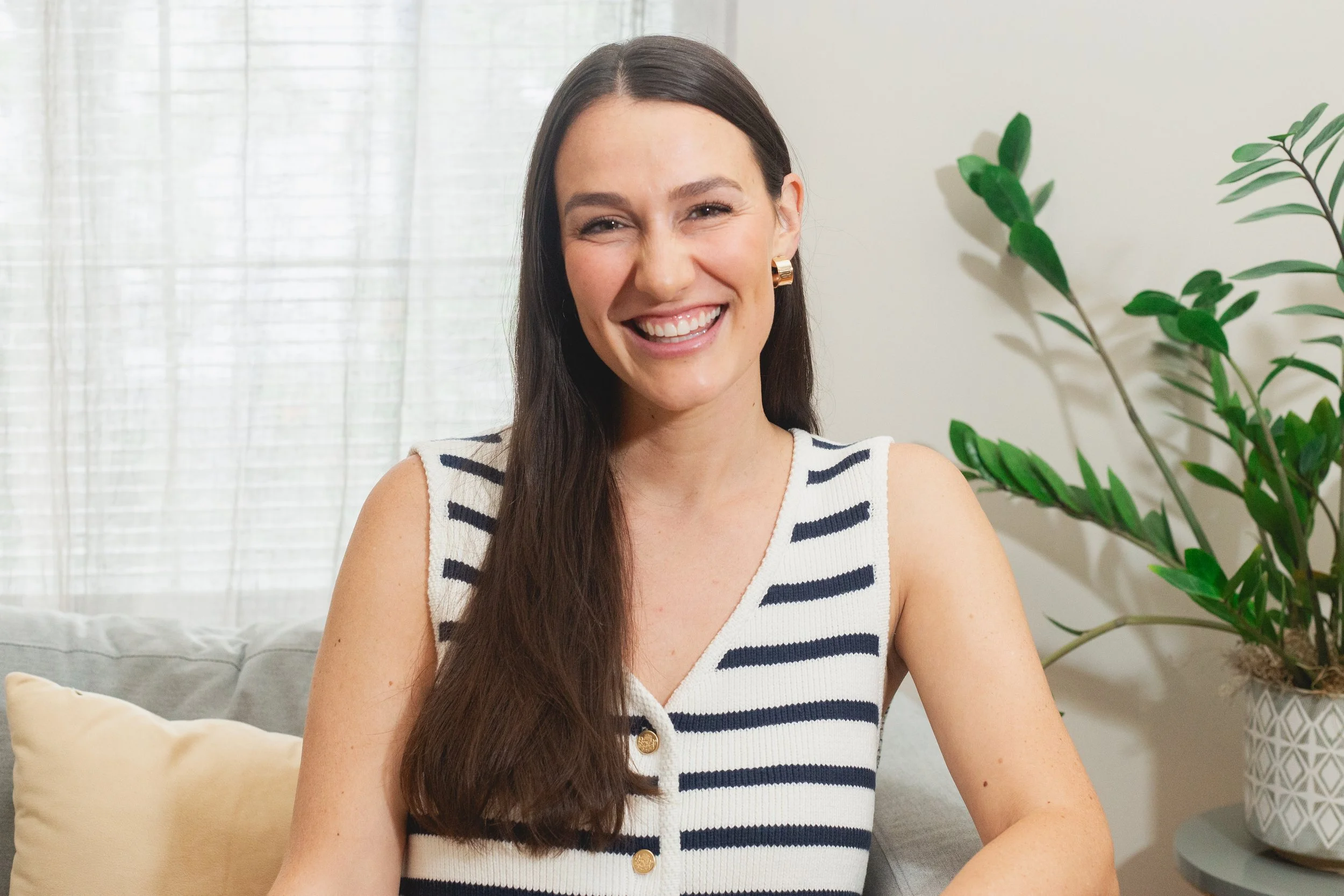 Katherine Healy woman wearing a striped top, sitting indoors with plant in background.