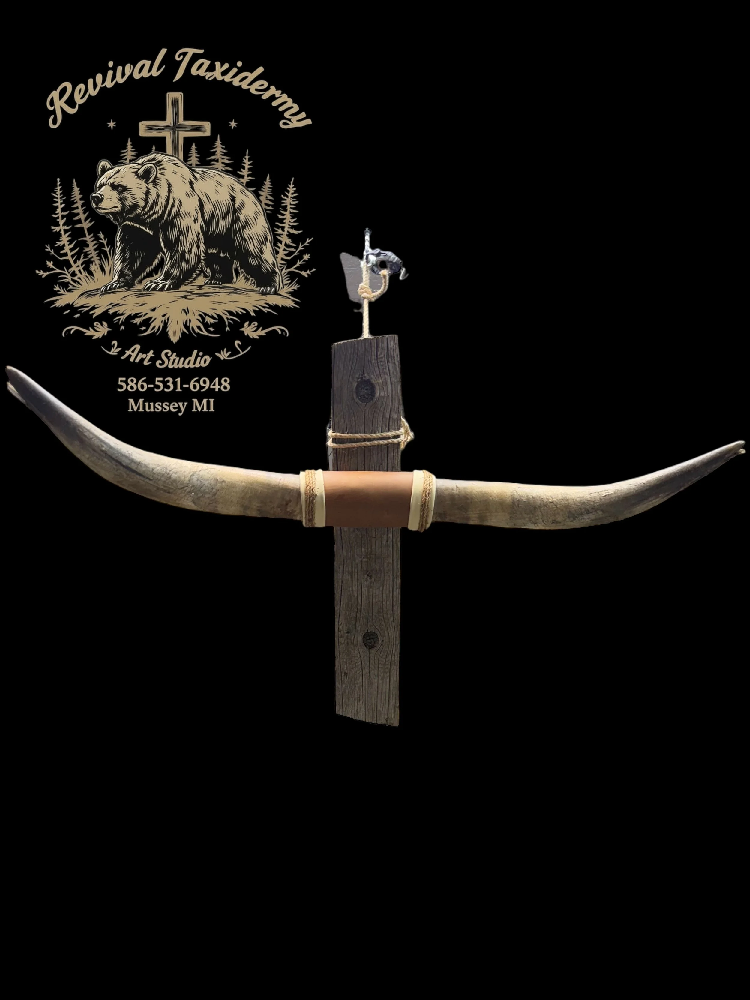 A decorative wall piece featuring a pair of antlers mounted on a wooden plaque, with a small bird sculpture perched on top. In the background, there is a logo with a bear, trees, a cross, and text that reads 'Revival Taxidermy Art Studio, 586-531-694