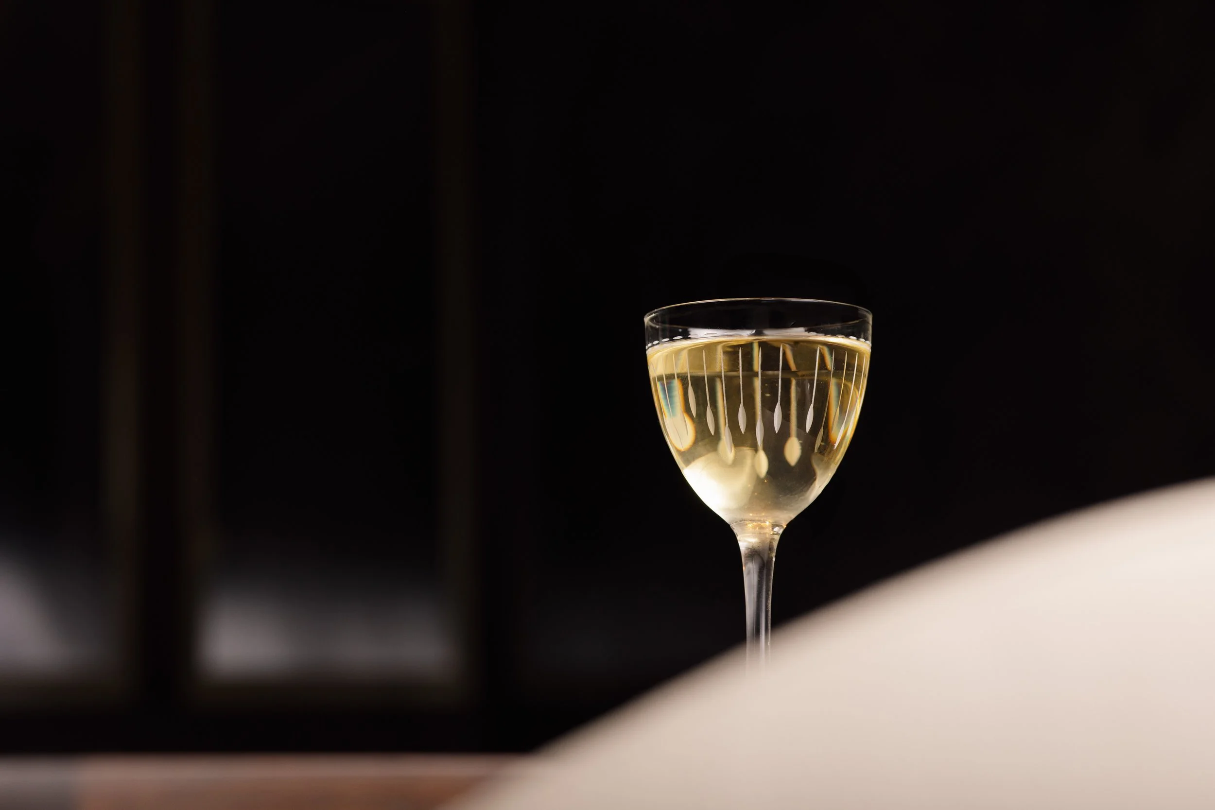 A single glass of sparkling wine on a white-linened table at Class Act.
