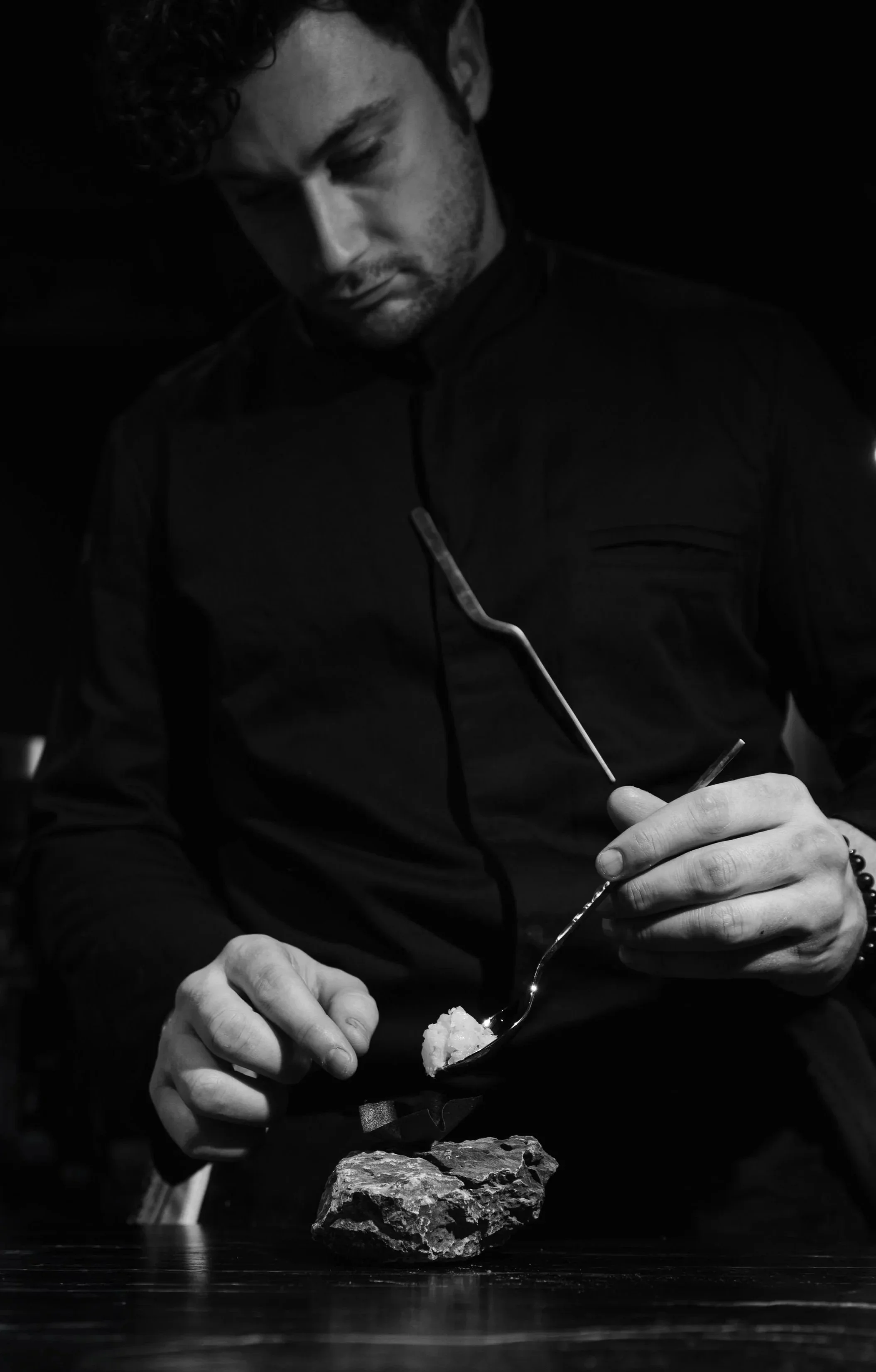 Chef Nicolai Mlodinow plating a course with tweezers, photographed in black and white.