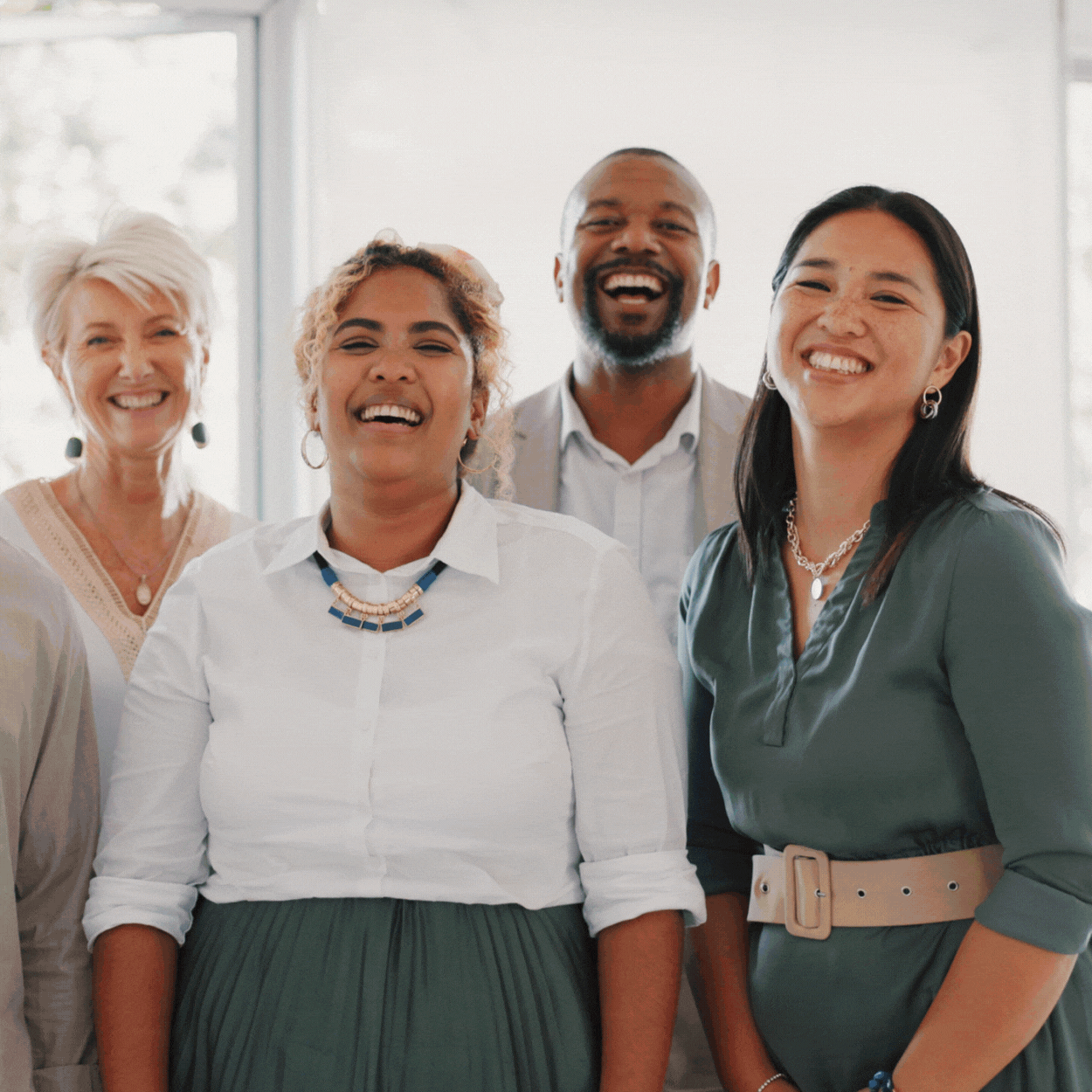 Group of five diverse people smiling in a well-lit indoor space.