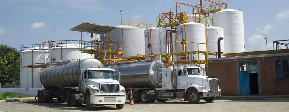 Vacuum tanker trunks are parked outside of an oil refinery