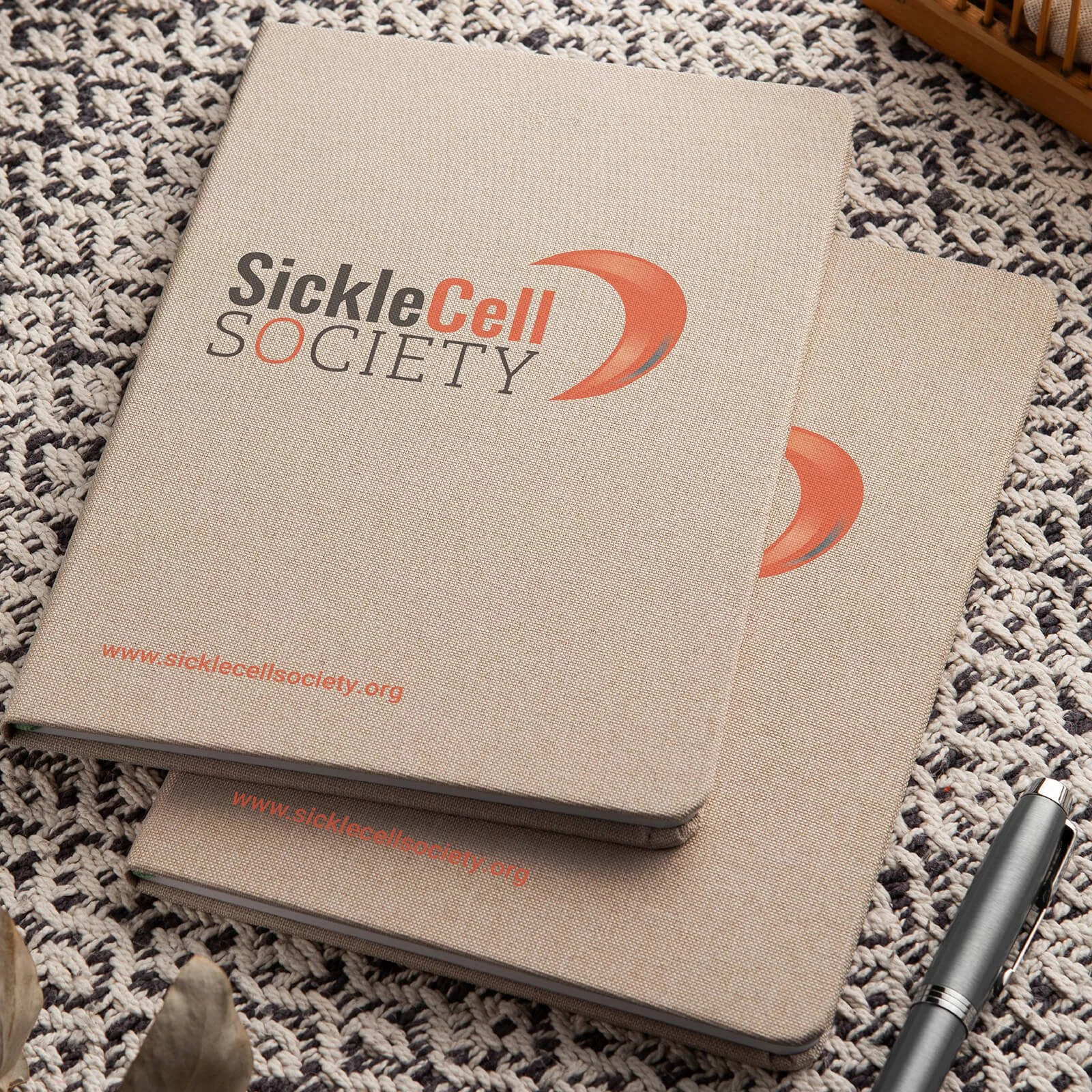 Brown notebooks with the new Sickle Cell Society logo
