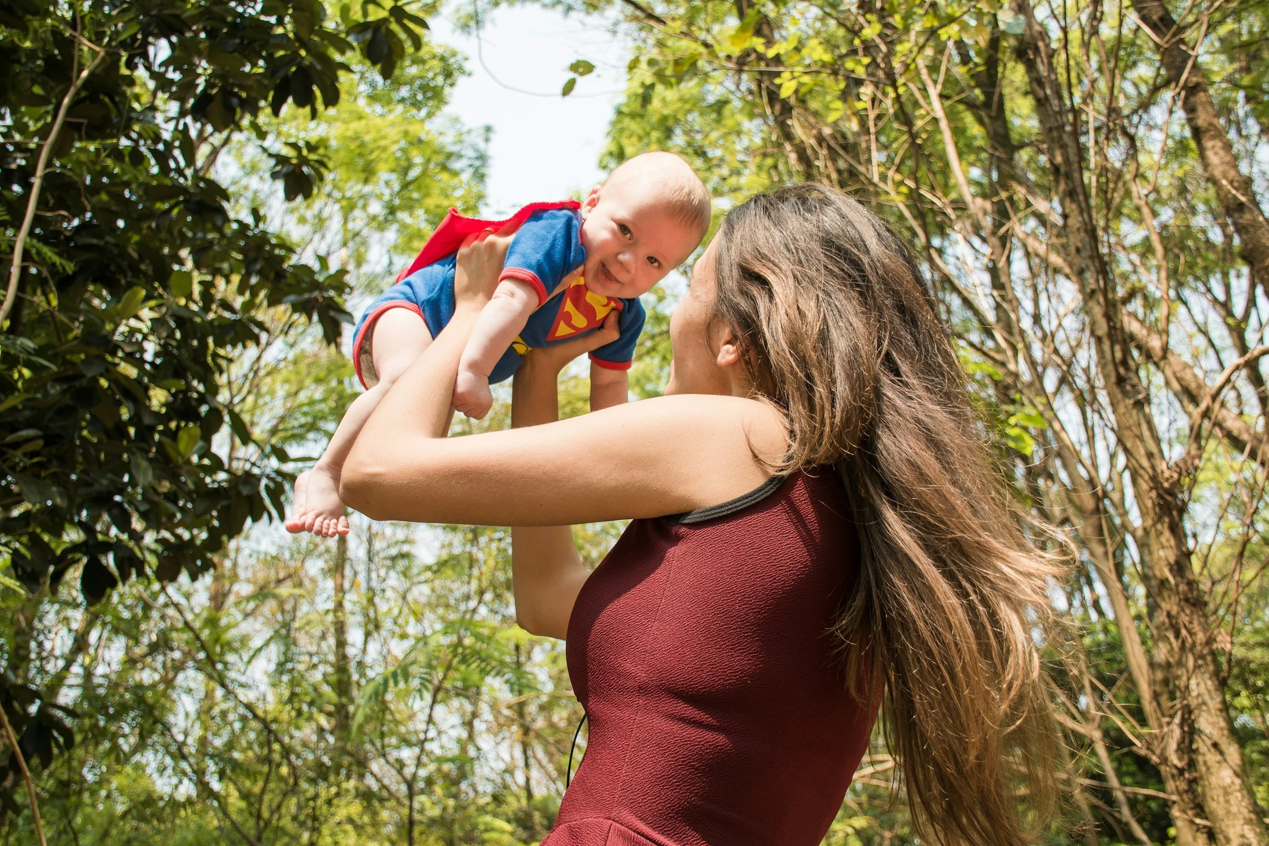image of mother holding her young baby above her head. both are smiling at each other.