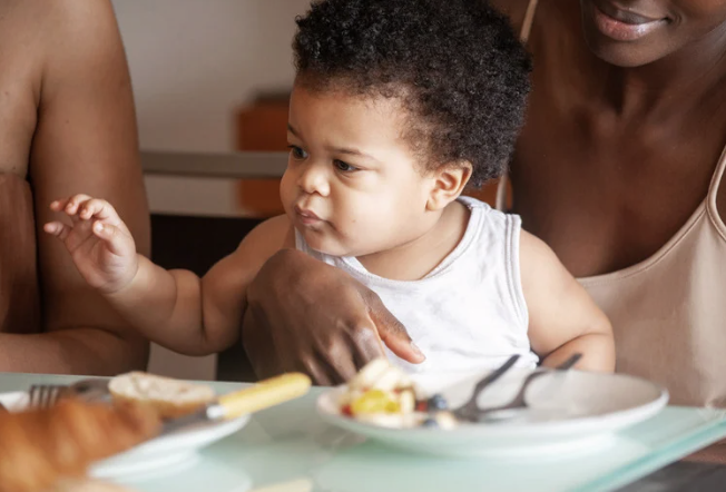 image of a child sitting on his mother's lap during a family meal.