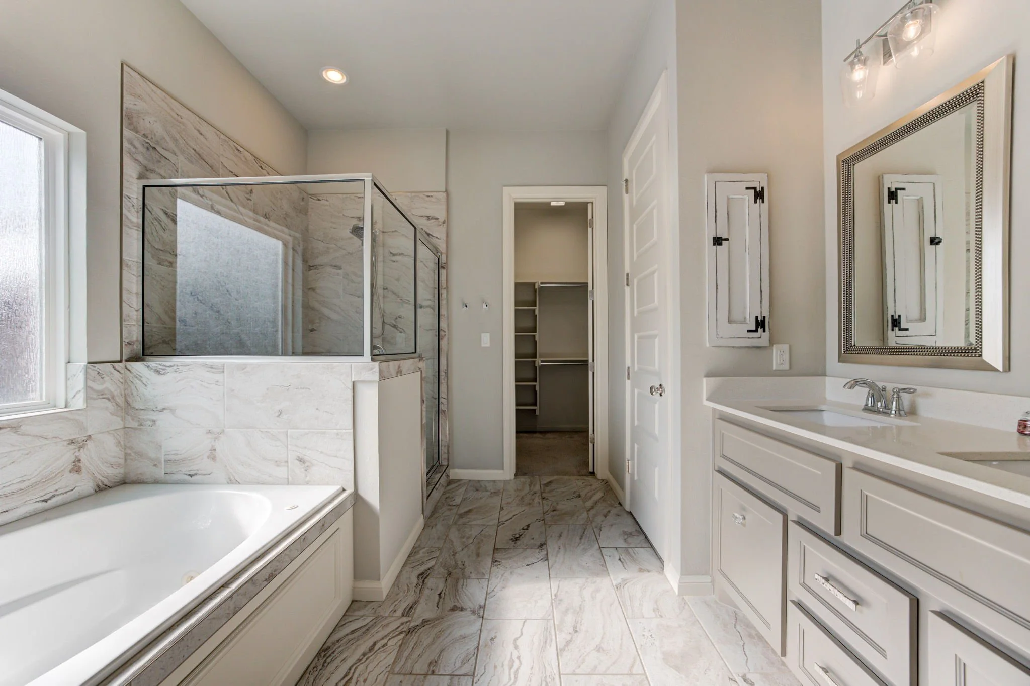 Modern bathroom with bathtub, walk-in shower, white cabinetry, and a large mirror.