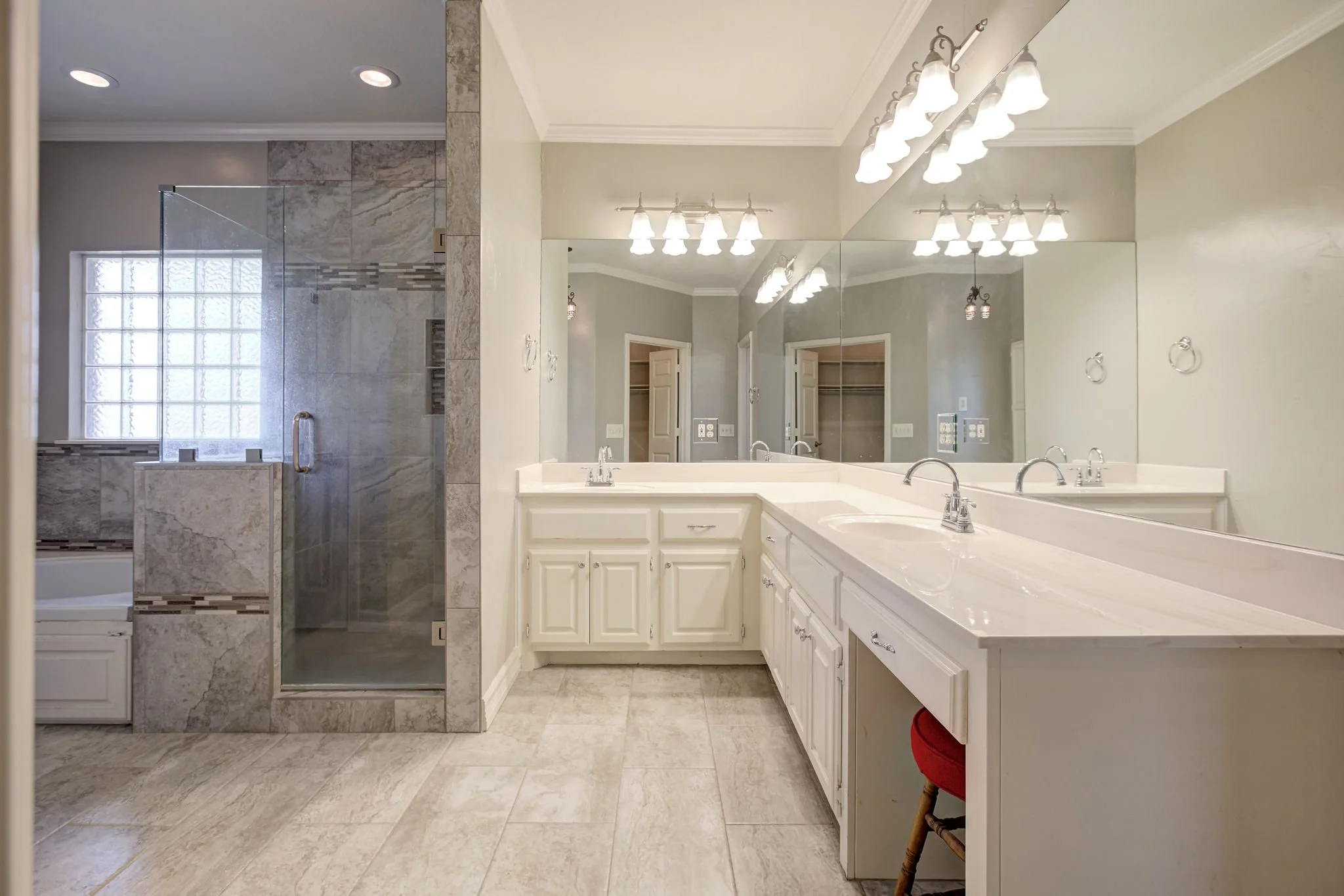 Bathroom with large mirror, double sinks, vanity cabinet, and shower with glass door.