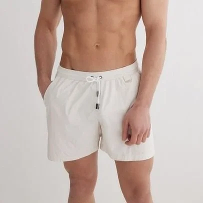 A man wearing white shorts with a drawstring, standing against a plain background.