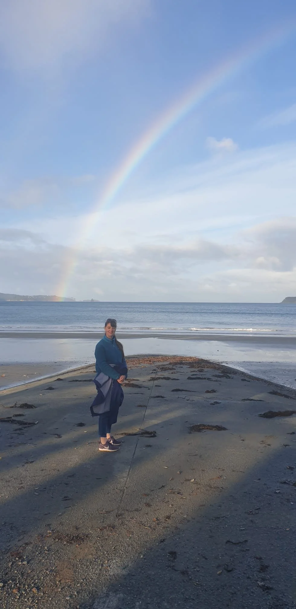 Sacha on the beach in front of a rainbow