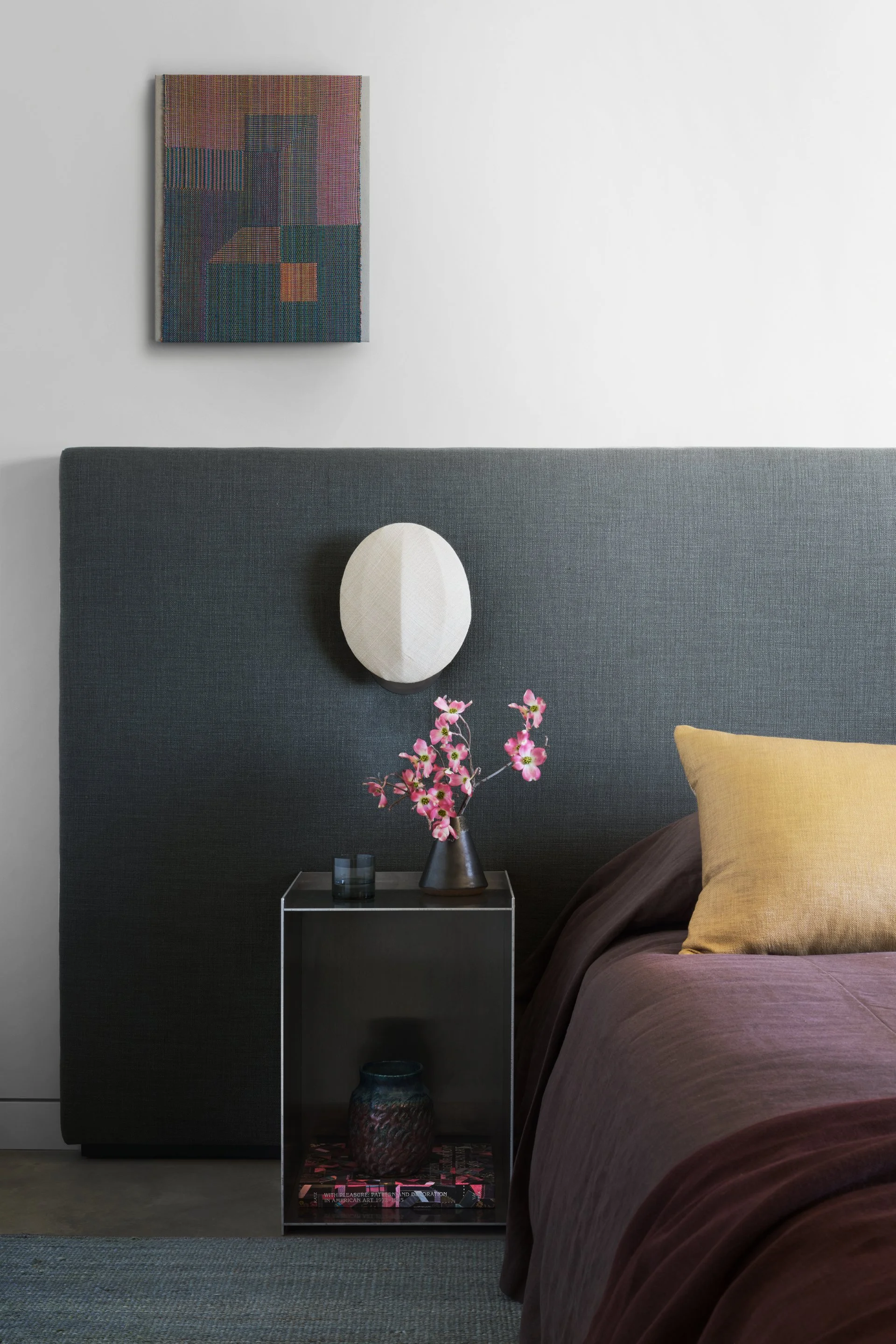 Modern bedroom styling with custom nightstand, abstract artwork, and layered textiles