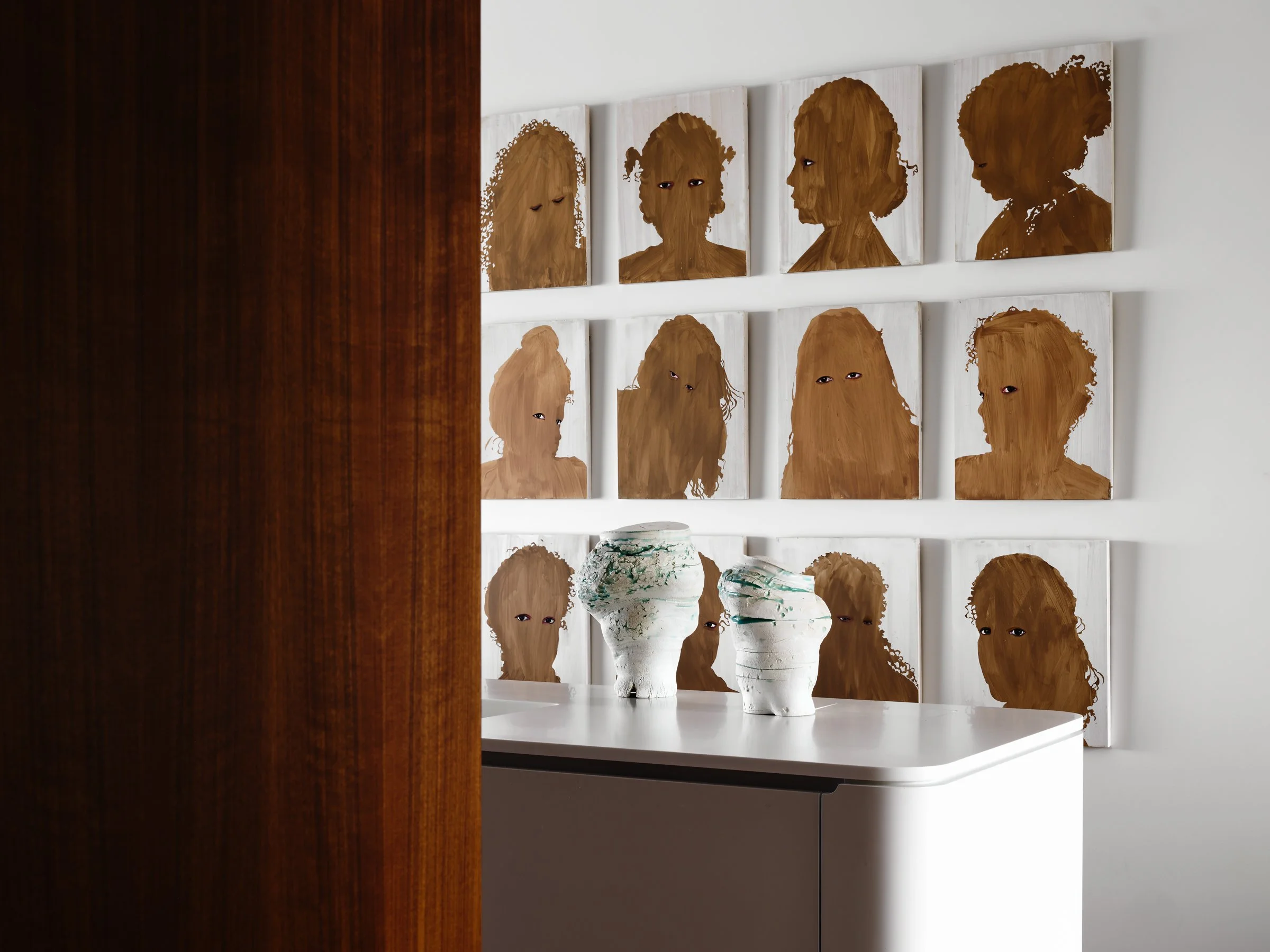 Grid of Firelei Báez portrait paintings above a custom sideboard with ceramic vessels — curated art collection in the Russian Hill San Francisco residence by Studio Collins Weir