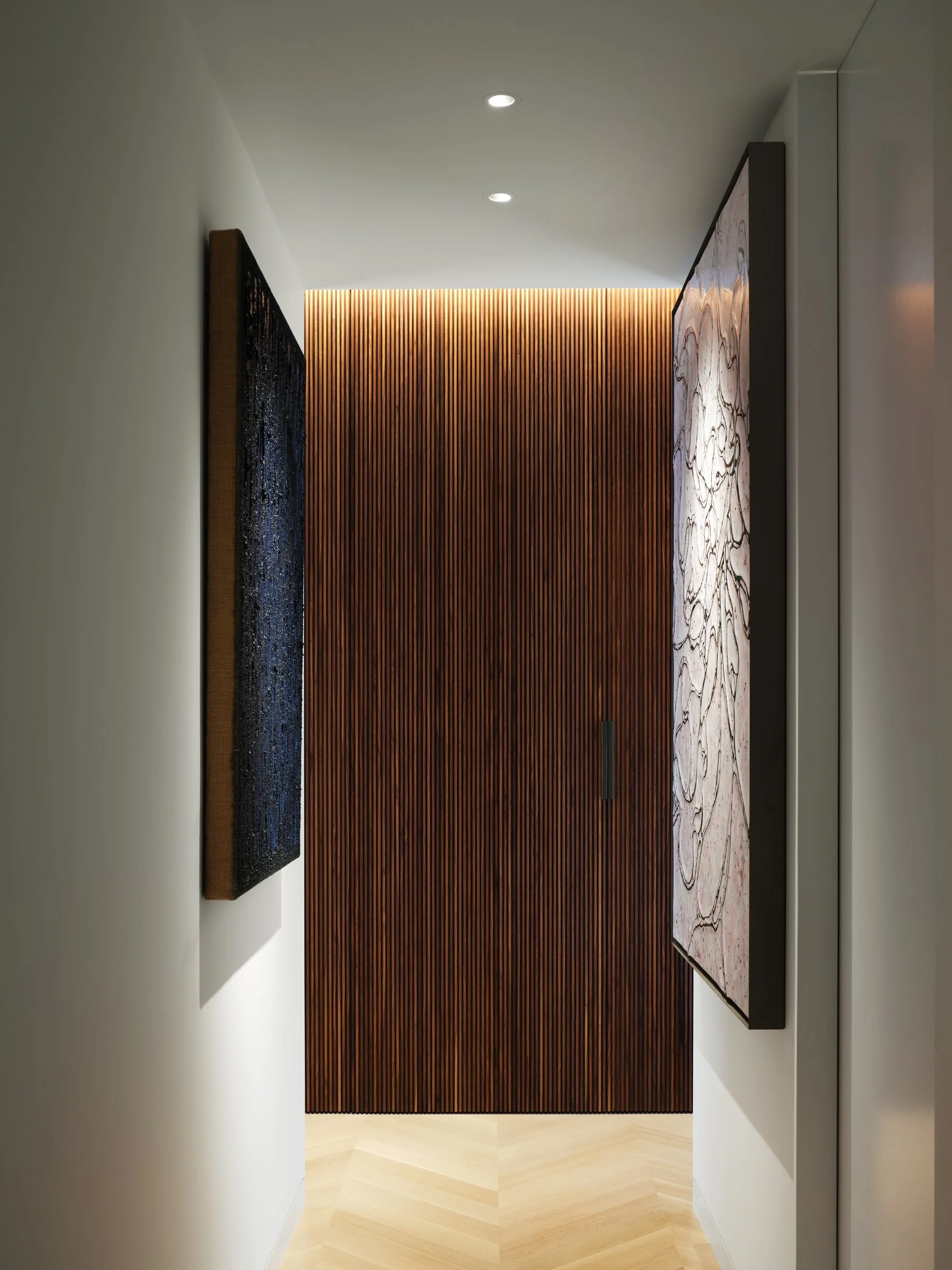 Art-lined entry hallway with custom slatted black walnut cabinetry, Ha Chong-Hyun painting on the left and contemporary figurative artwork on the right — Russian Hill San Francisco interior design by Studio Collins Weir