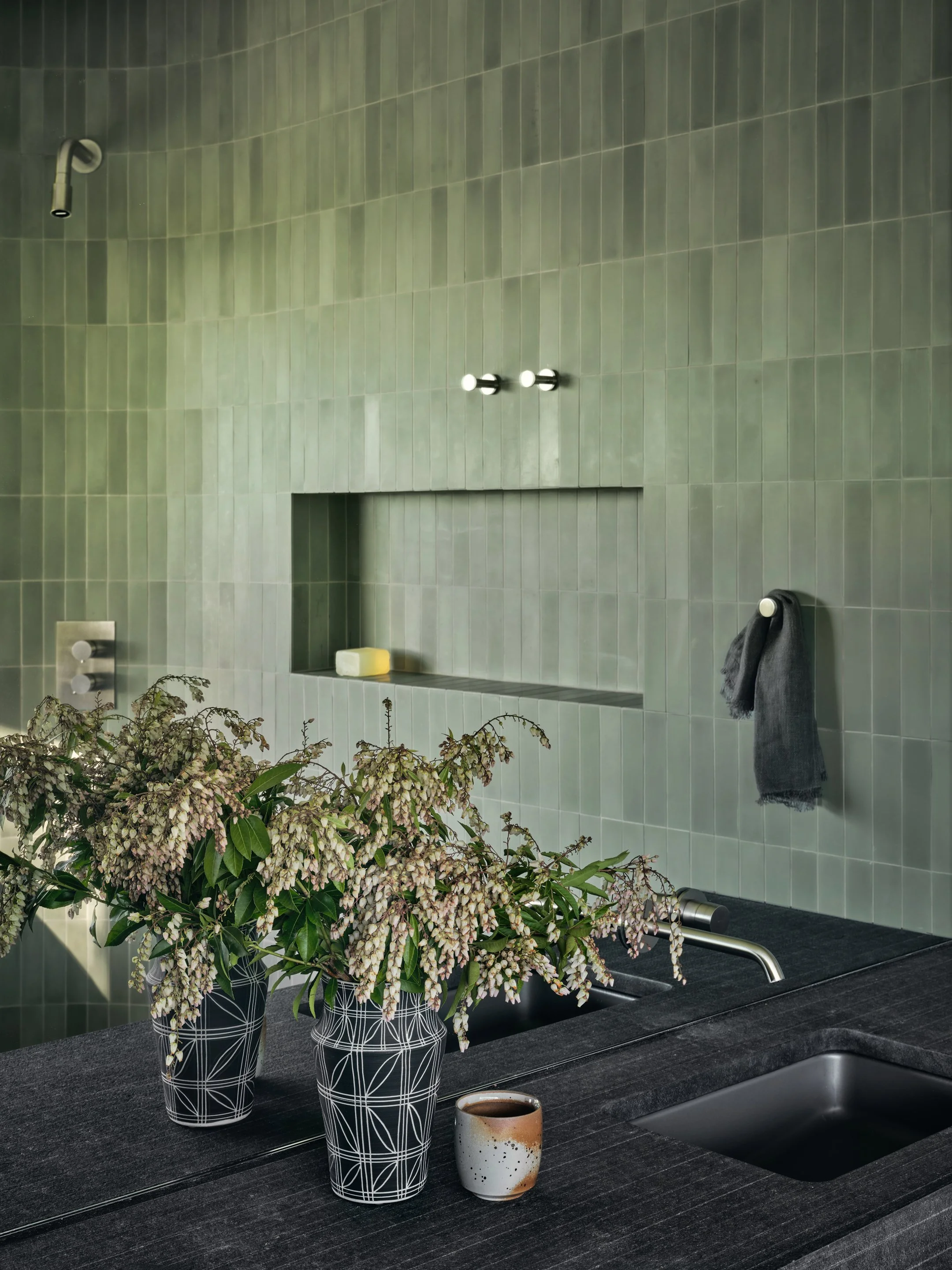 Modern bathroom detail with green tile wall, recessed niche, and dark stone countertop