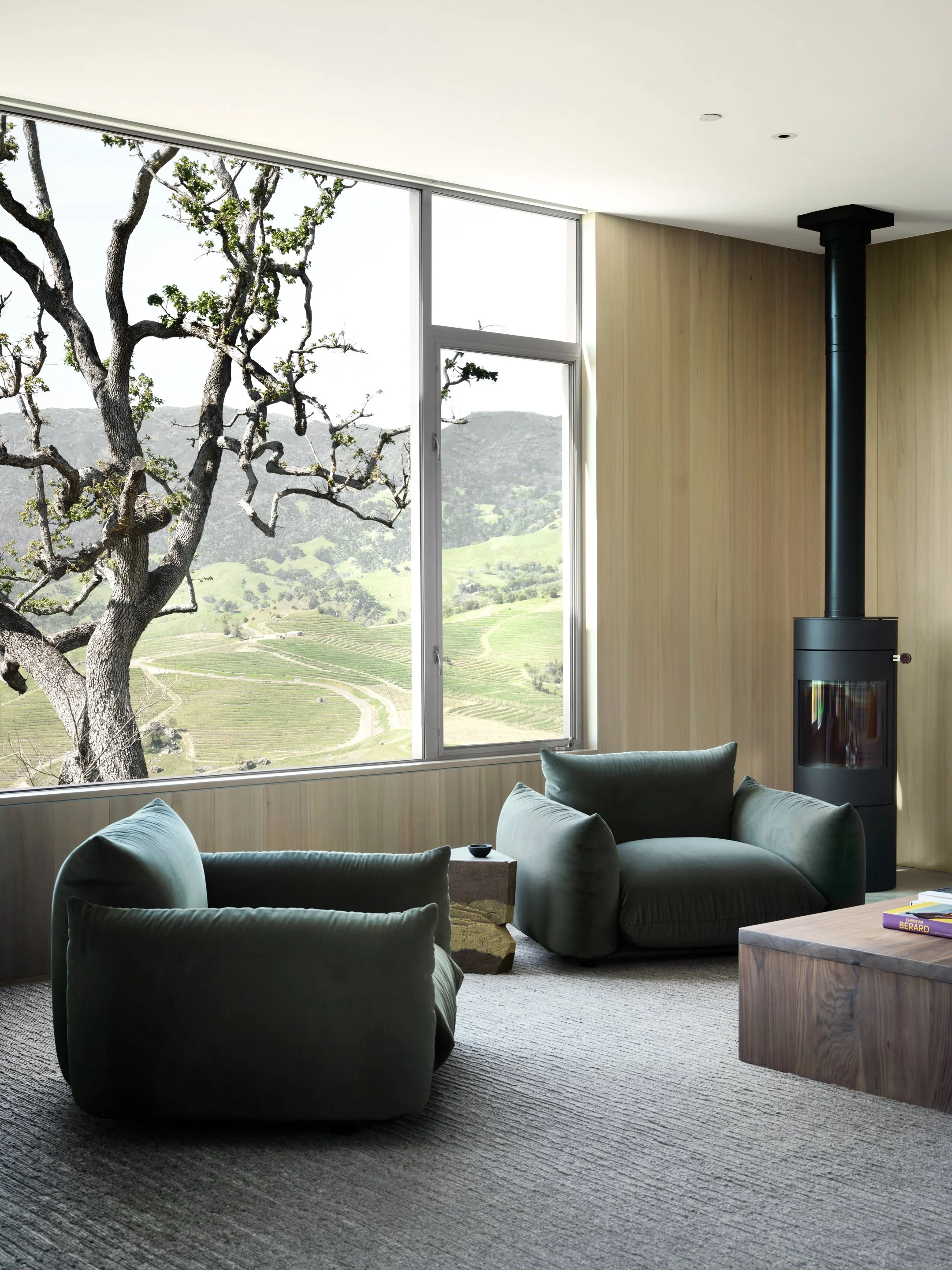 Modern living room with oversized windows, landscape views, and custom upholstered lounge chairs