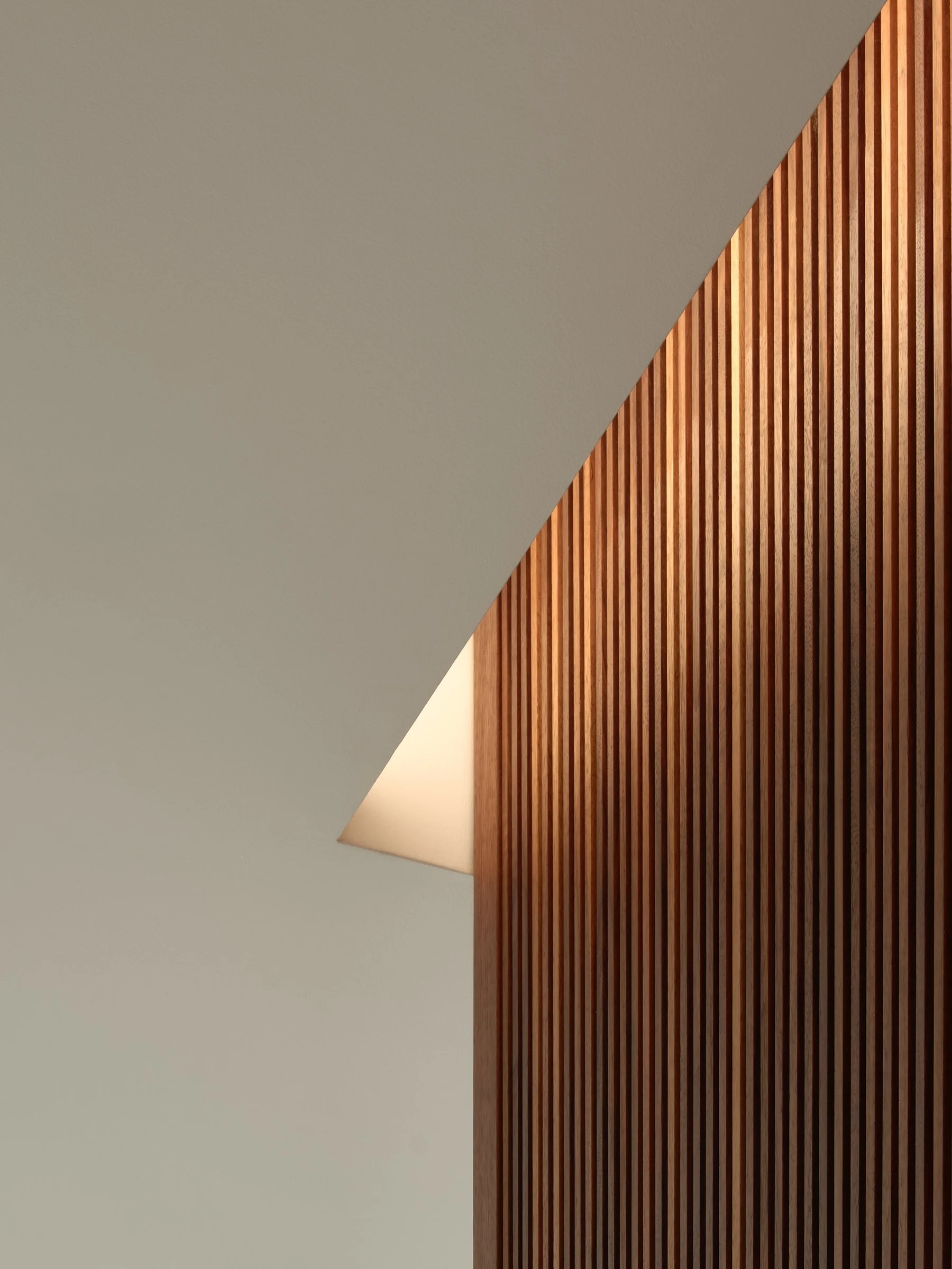 Architectural detail of custom slatted black walnut cabinetry with integrated cove lighting casting a warm diagonal shadow — bespoke millwork by Studio Collins Weir, Russian Hill San Francisco
