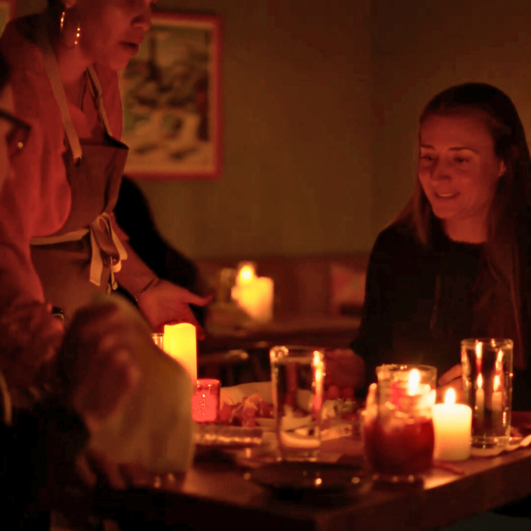 People gathered around a table with lit candles in a dimly lit room.