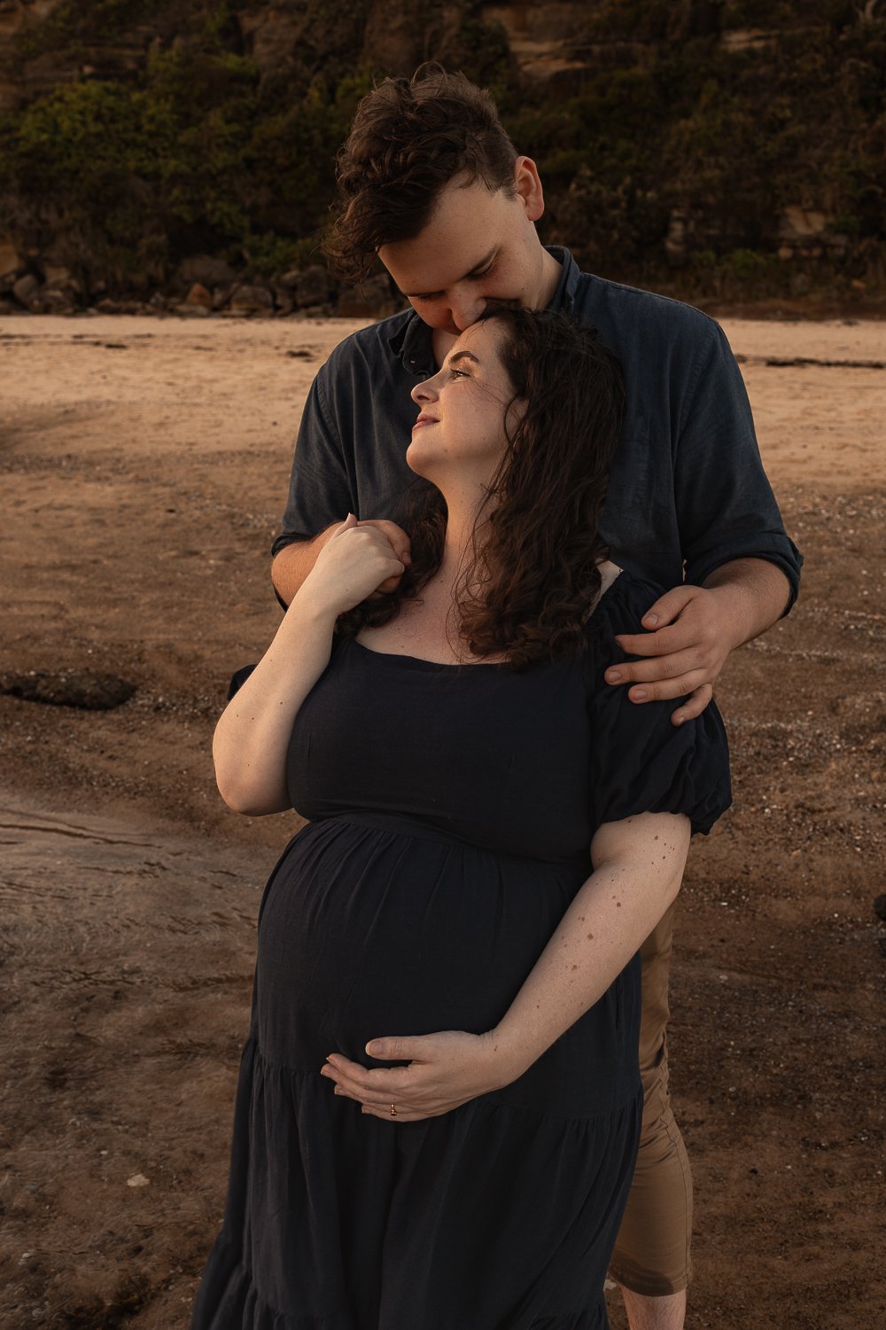 Nicole Johnson Photography ~ Maternity photography session beach location, parents embracing looking towards sunset