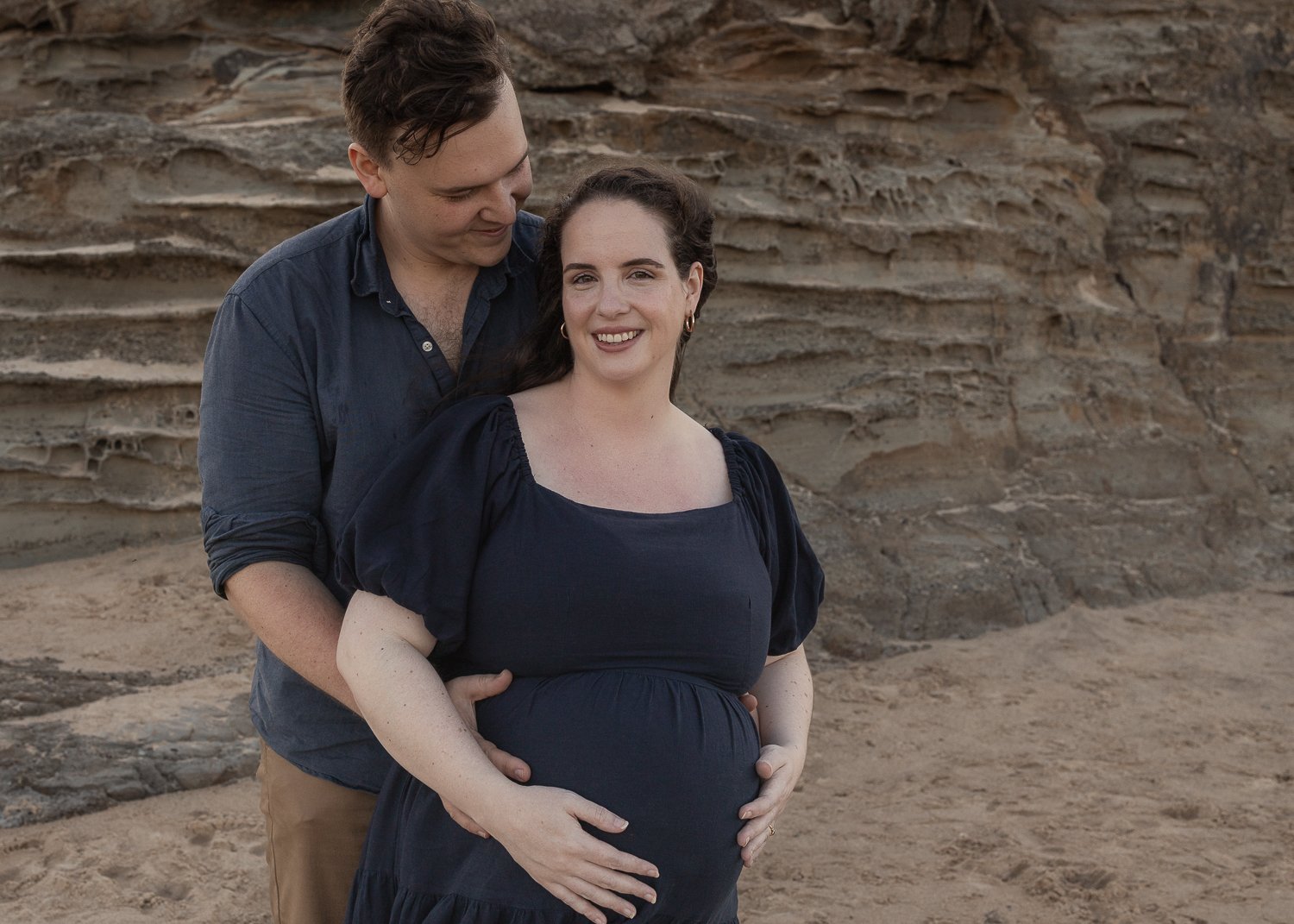 Nicole Johnson Photography ~ Maternity Beach session, parents embracing in front of cliff face