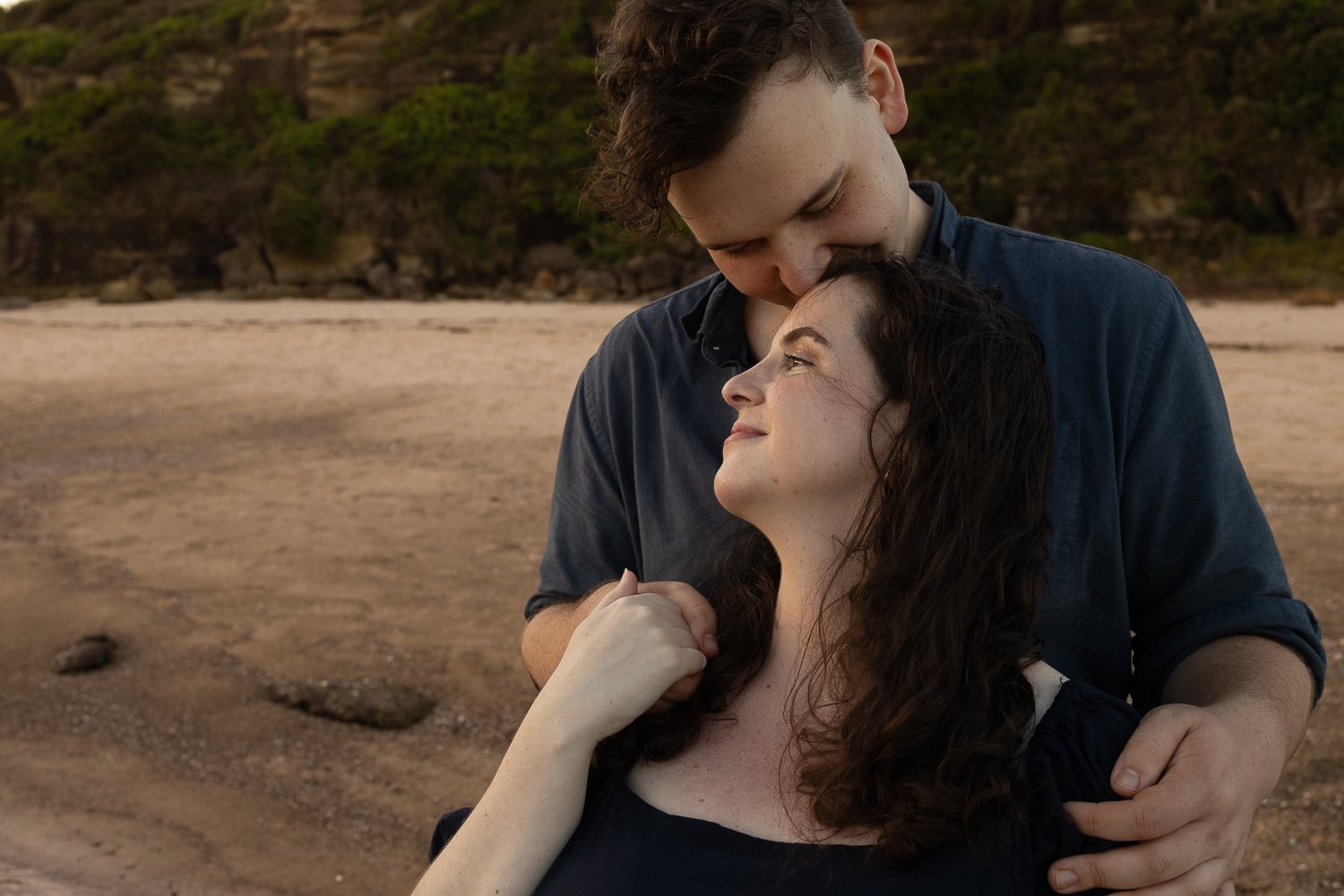 Nicole Johnson Photography ~ Maternity beach session, couple embracing looking towards sunset