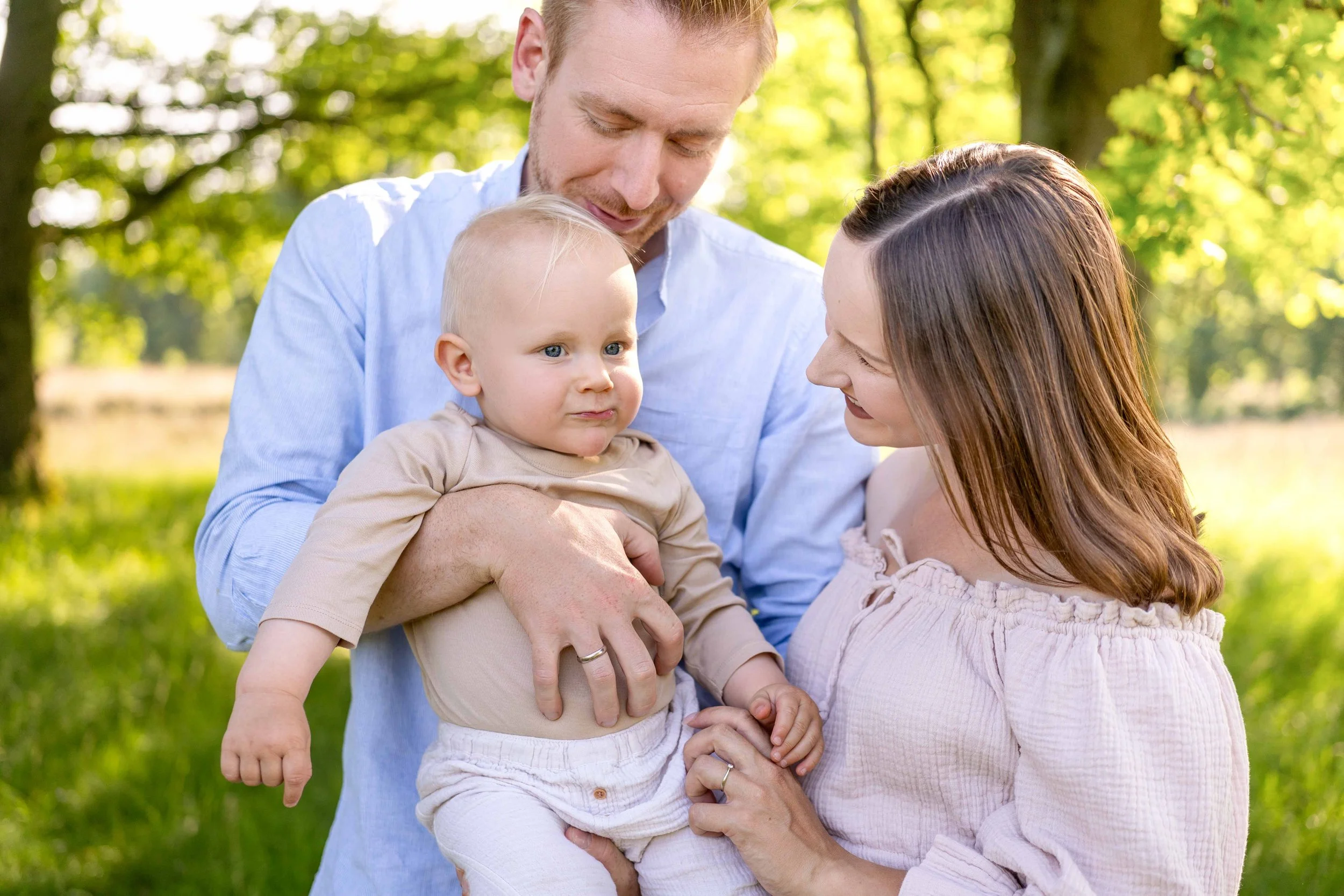 Ein Mann und eine Frau halten ein Baby im Park.