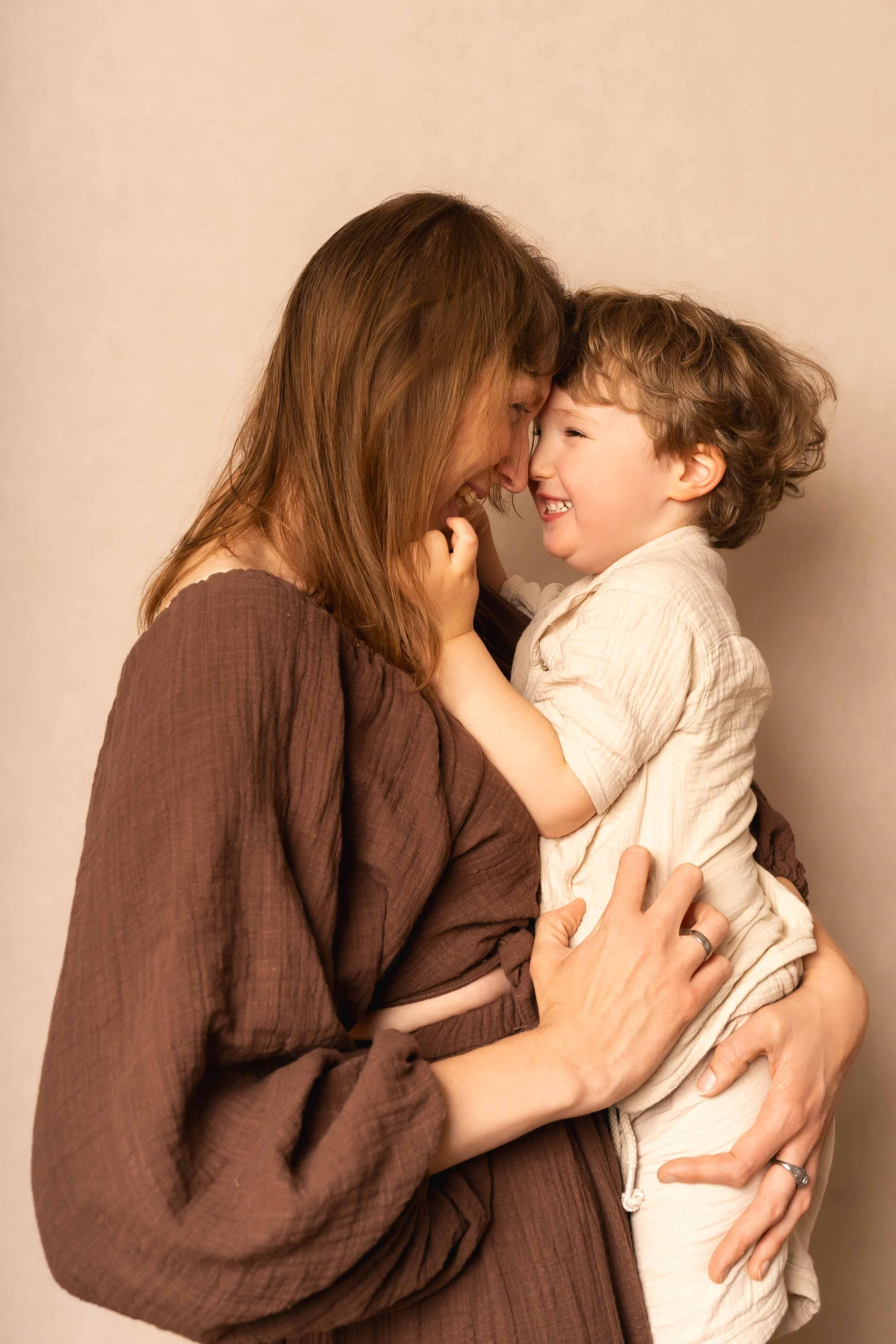 Eine Frau hält ein lachendes Kind hoch, beide berühren sich mit Stirnen, Freude