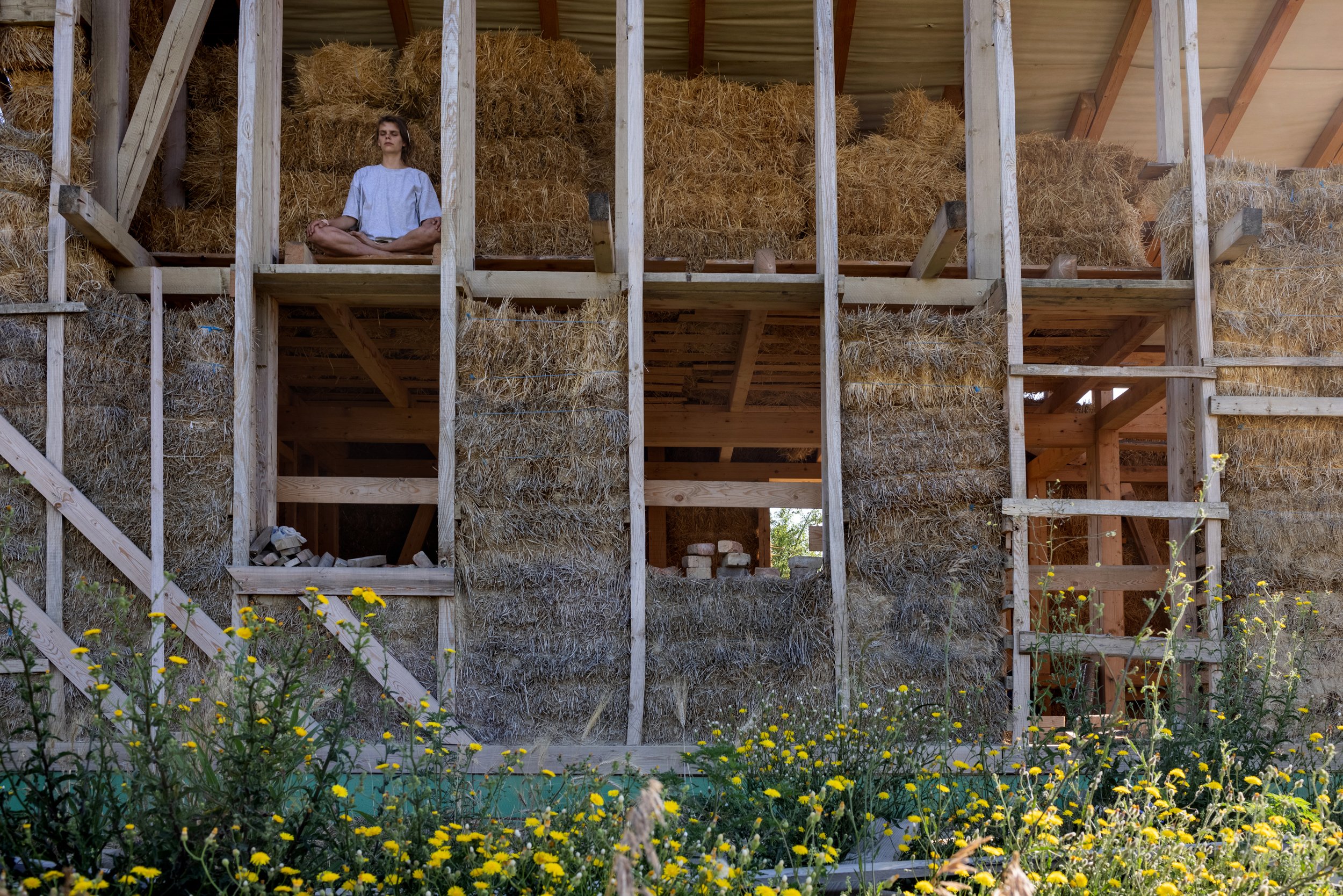  Sonja meditating on the floor of a straw bale house overlooking the Eco-meadow in Nyim on July 3, 2022. The Finnish volunteer spent six months with the community in Somogy County in the framework of the ESC (European Solidarity Corps) program, learn