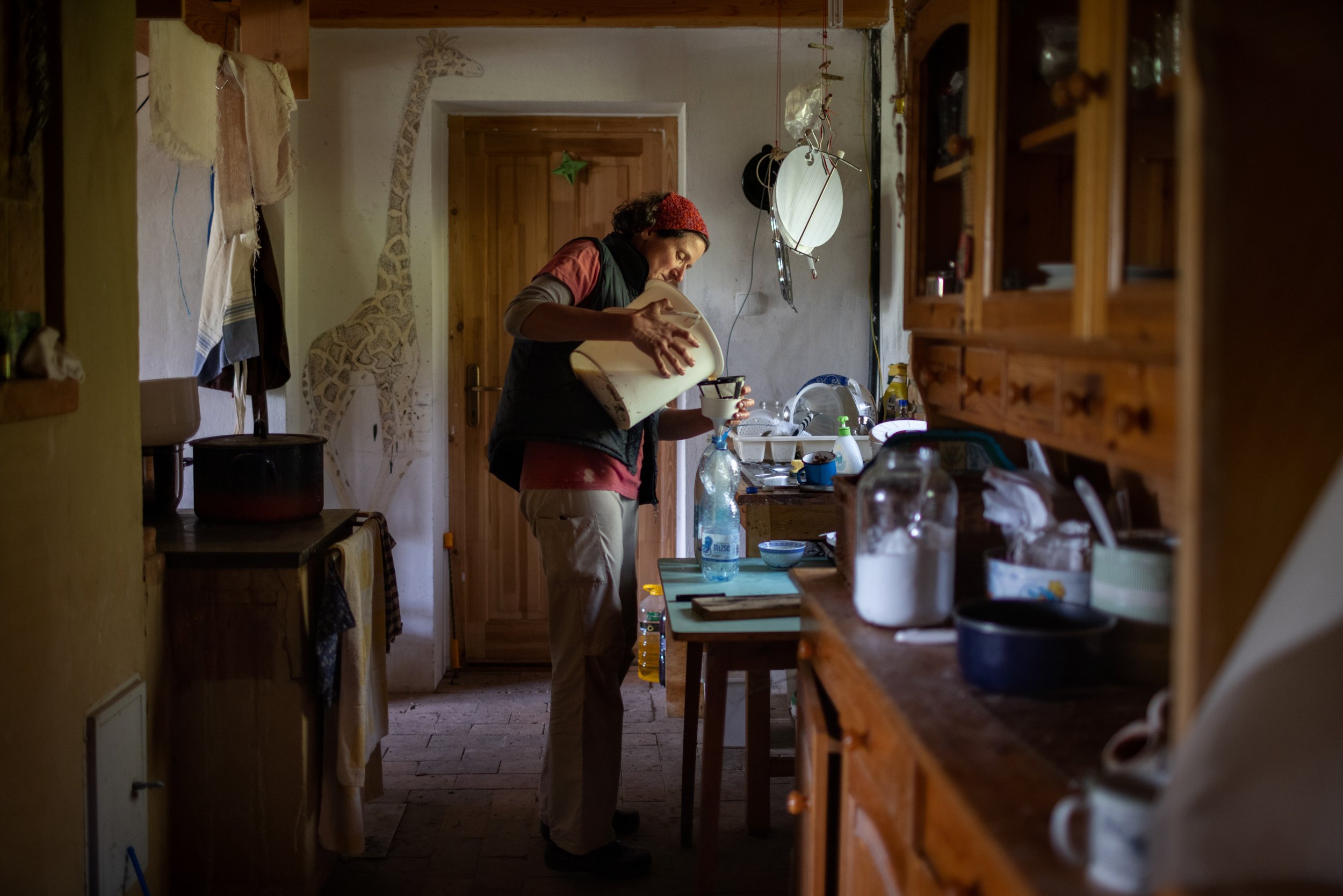  Etelka dispensing  fresh milk in her kitchen in Nagyszékely on May 11, 2022. She and her daughters  moved from the capital to the village in 2008, where they set up for self-sufficiency in food. Through experience and overcoming many difficulties, t