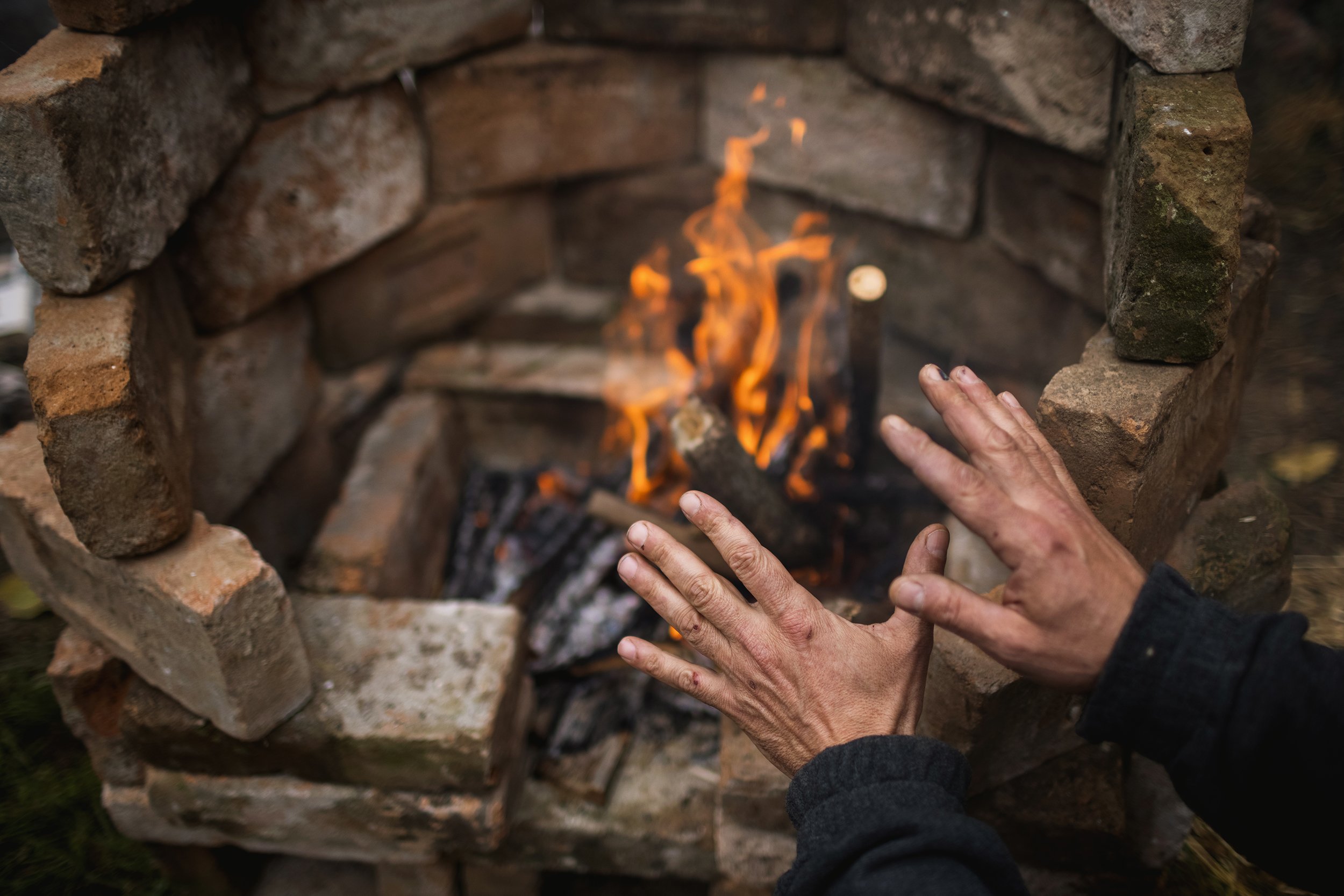  A participant warms up by the fire of the hastily built outdoor stove at the rocket stove building workshop of the Science of Nomad Life series launched in cooperation with a close friend of the community, Pál Szentgróti, and the community on Novemb