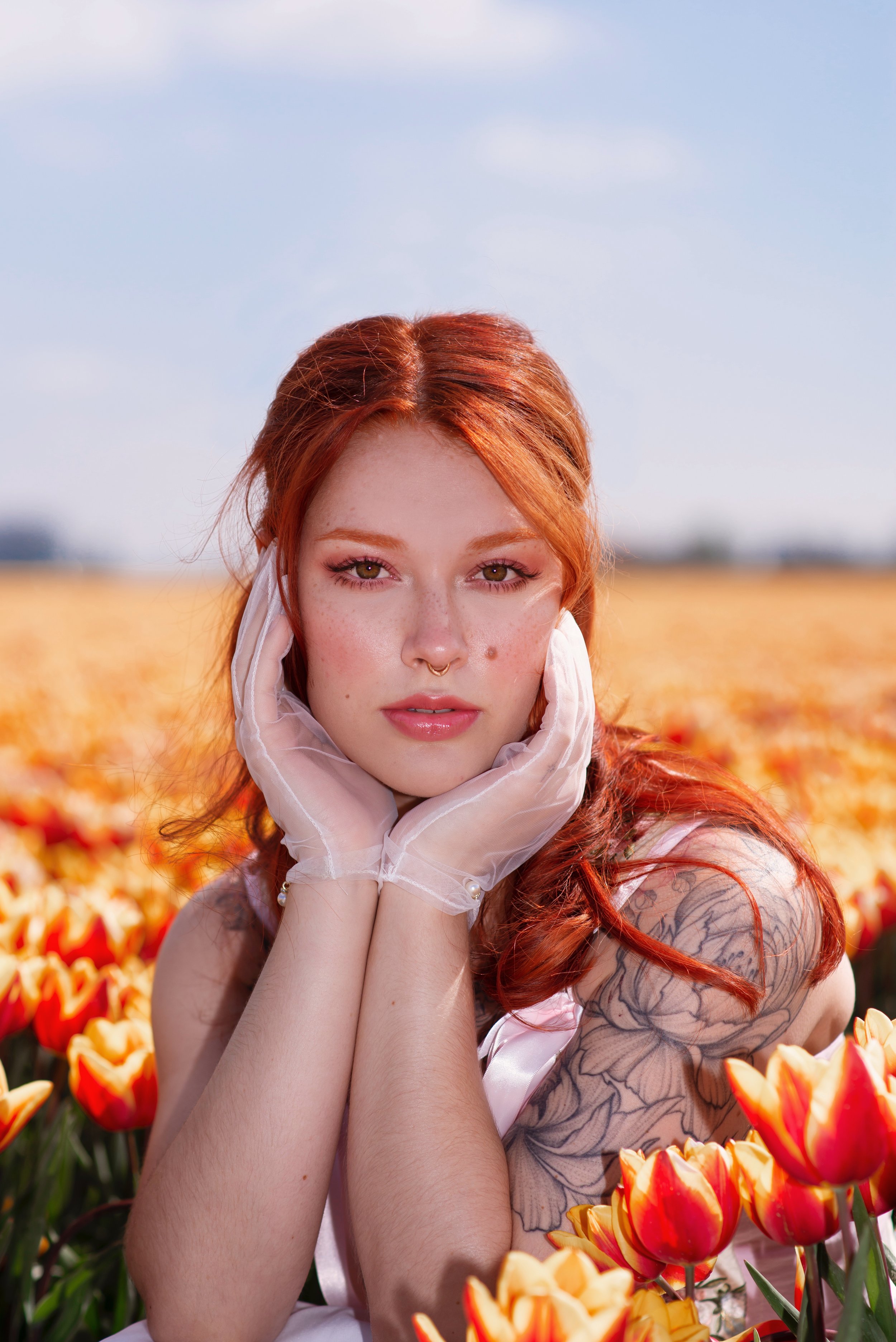 Dutch red head model with tattoos posing in a tulip field modelling a hand made corset.