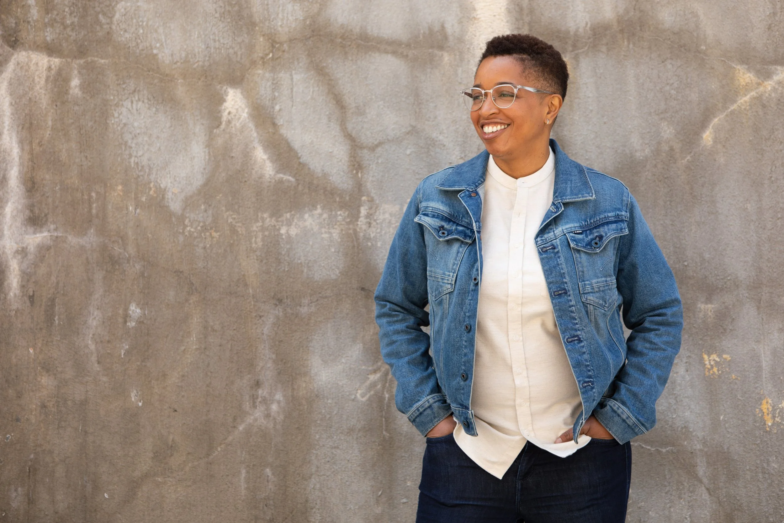 casual headshot of a woman in front of a concrete wall