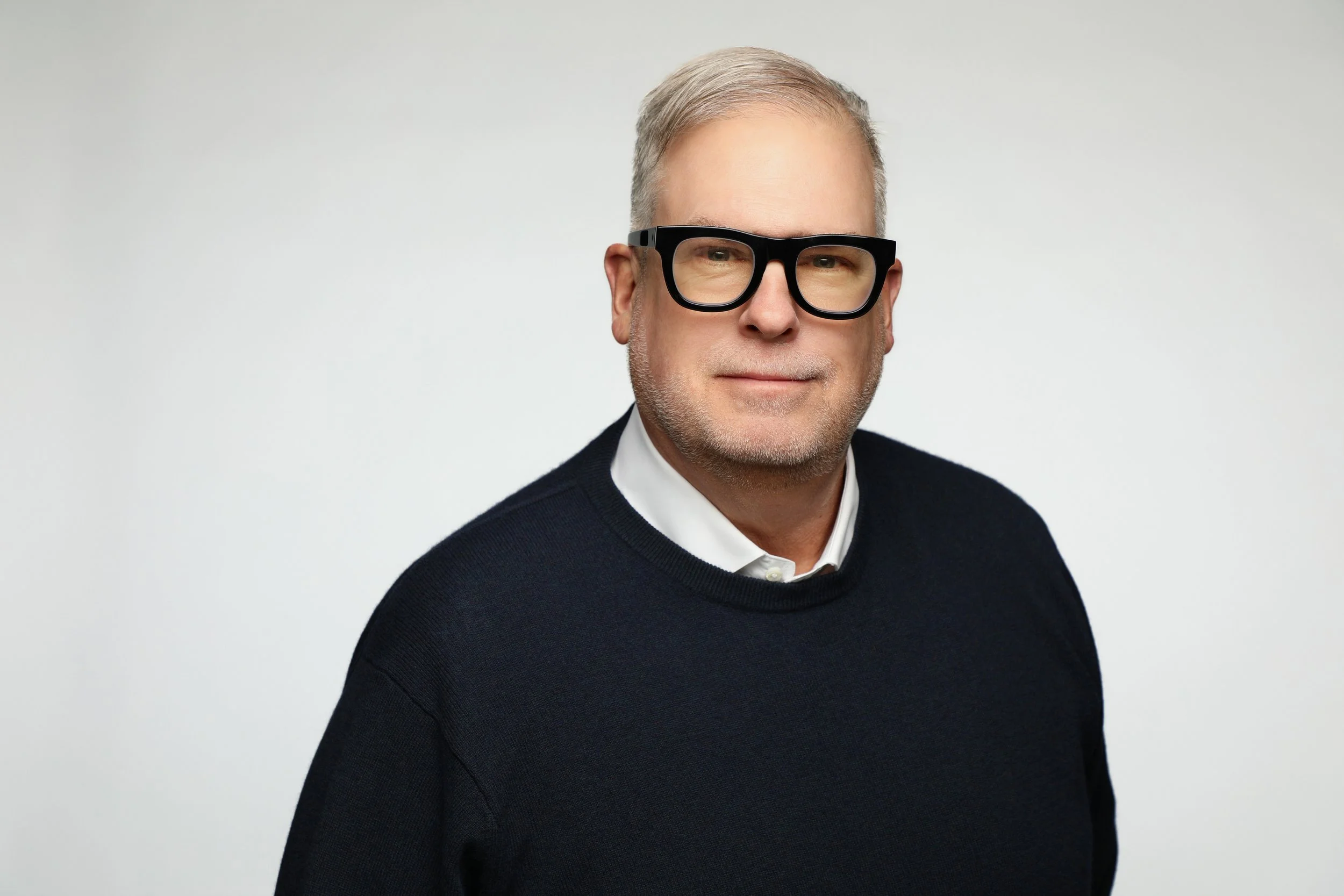 headshot of a man with glasses and a soft smile