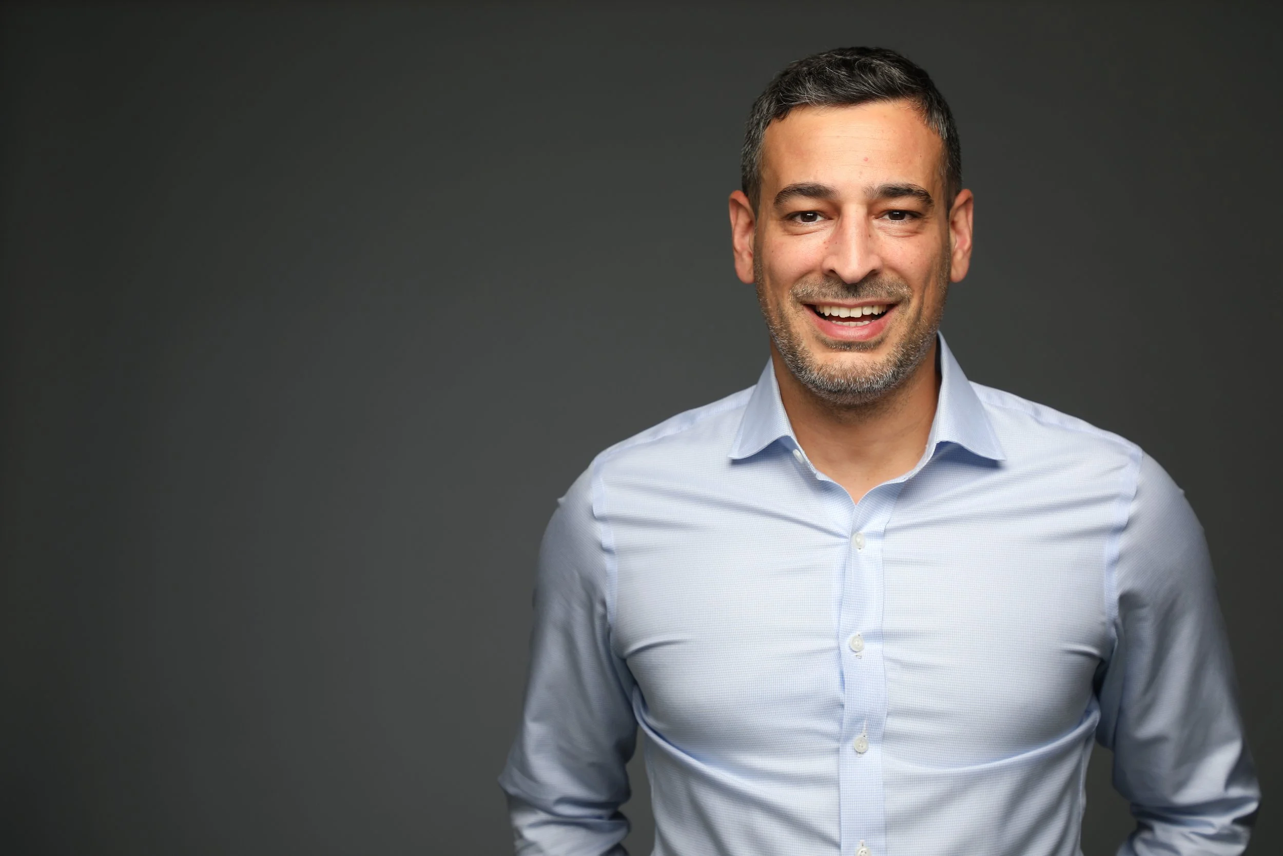 Headshot of a smiling man in a blue shirt