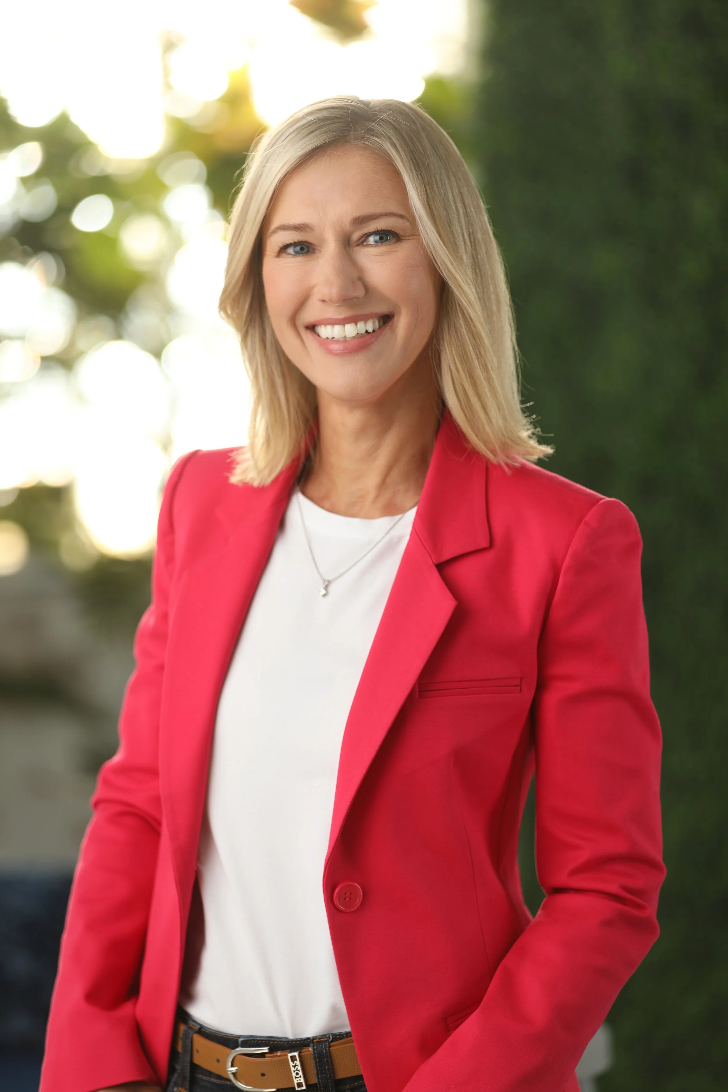 headshot of a woman in front of greenery and a window