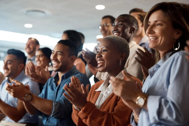 Group of people clapping and laughing indoors.