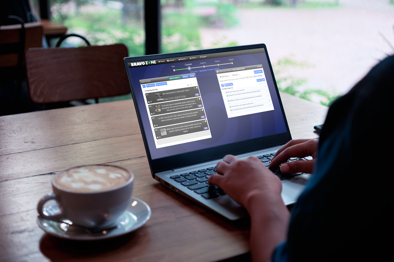 Person working on a laptop with a Hope is Propped on a wooden table in a cafe, with a cup of coffee nearby and a window showing greenery outside.