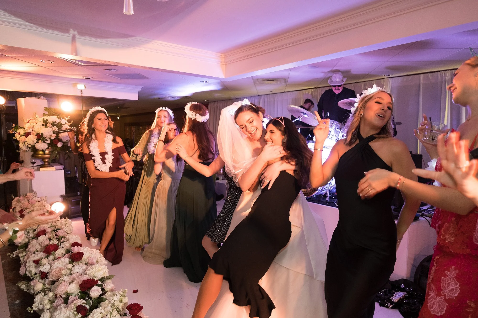 Women dancing and celebrating at a wedding reception with a band playing in the background.