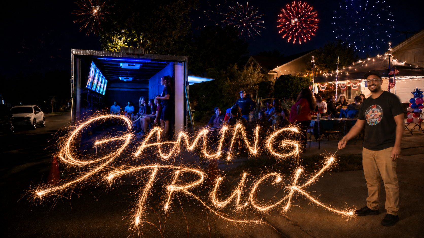 Long Exposure image of a man holding a sparkler and spelling out the words "GAMING TRUCK" in front of a residential 4th of July party.  There is fireworks overhead and kids playing inside the trailer.