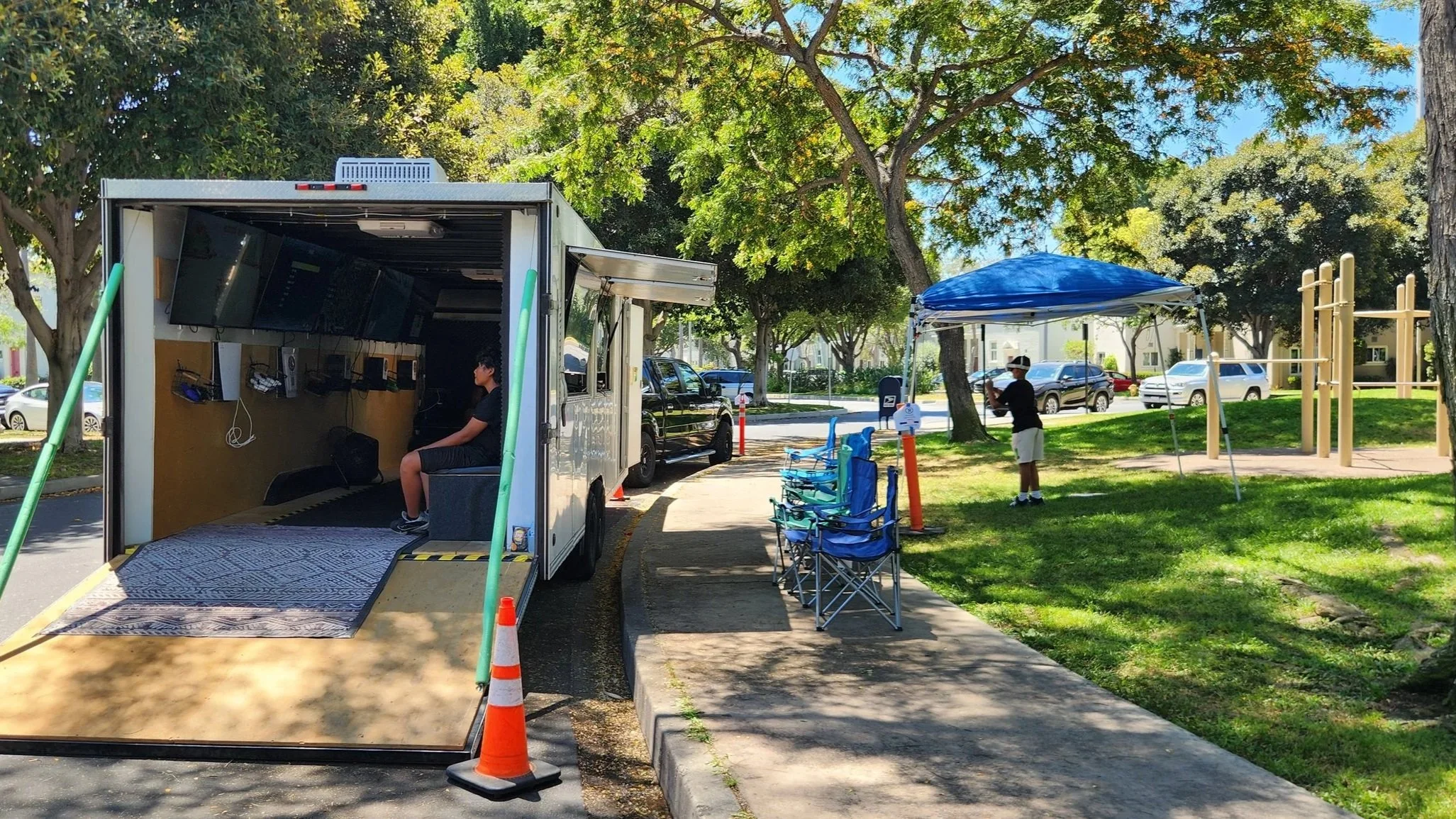 Party at the park -  A video game truck is parked curb side while a kid is under a canopy playing with a Oculus VR headset.