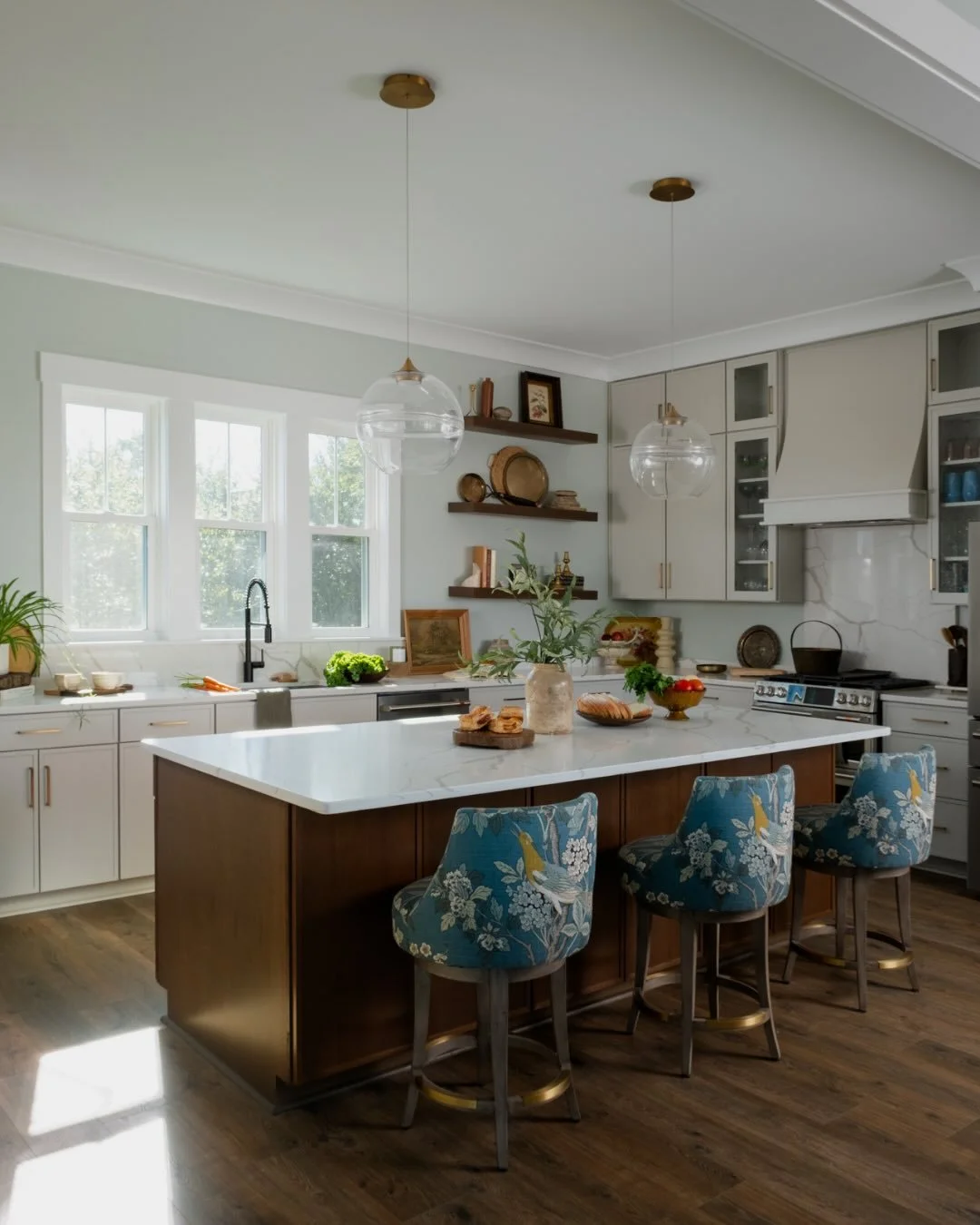 This kitchen strikes the perfect balance between light and contrast.

Soft gray-white cabinetry keeps the space bright, while the rich wood island adds warmth and depth. Open shelving and a built-in wine rack bring both style and function, and crisp 