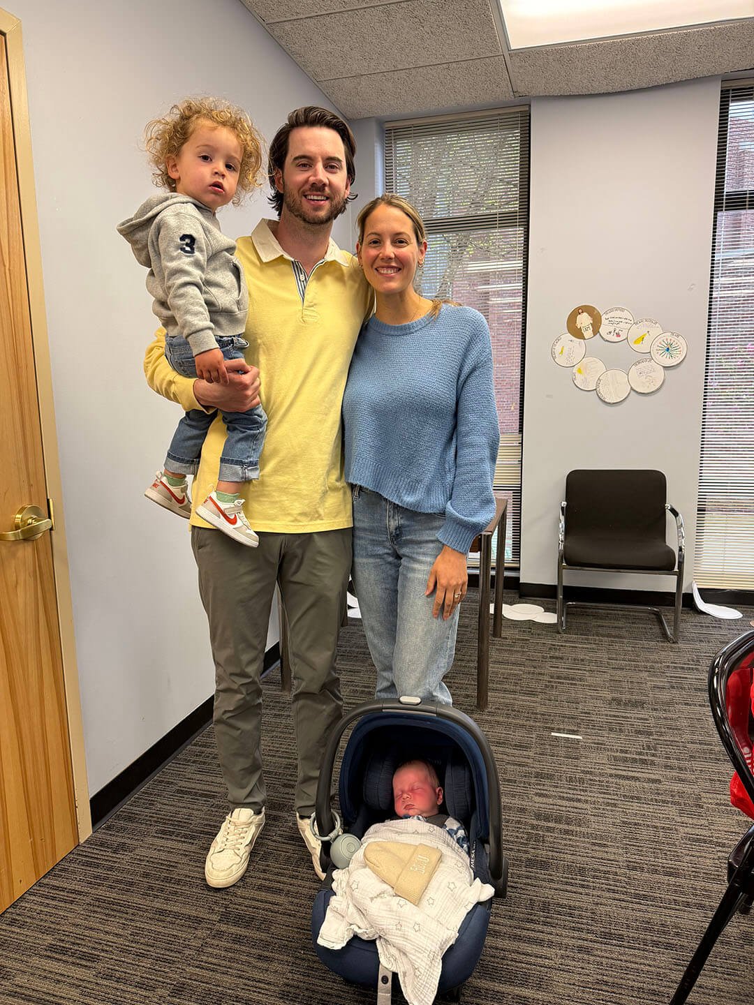 Family of young mother and father with baby and toddler, smiling in the Parish Center