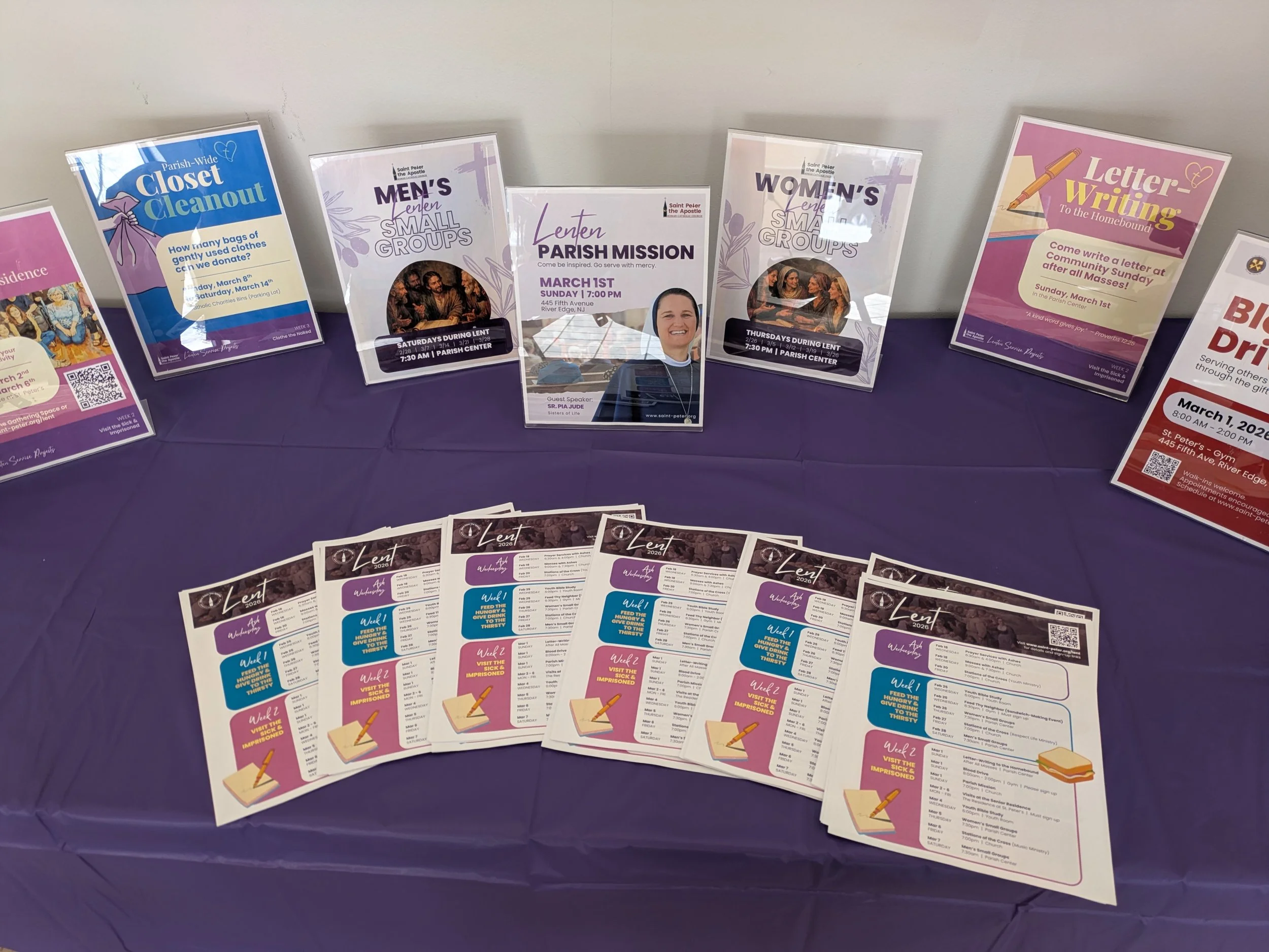 Table with purple tablecloth with neatly arranged flyers for various Lenten events