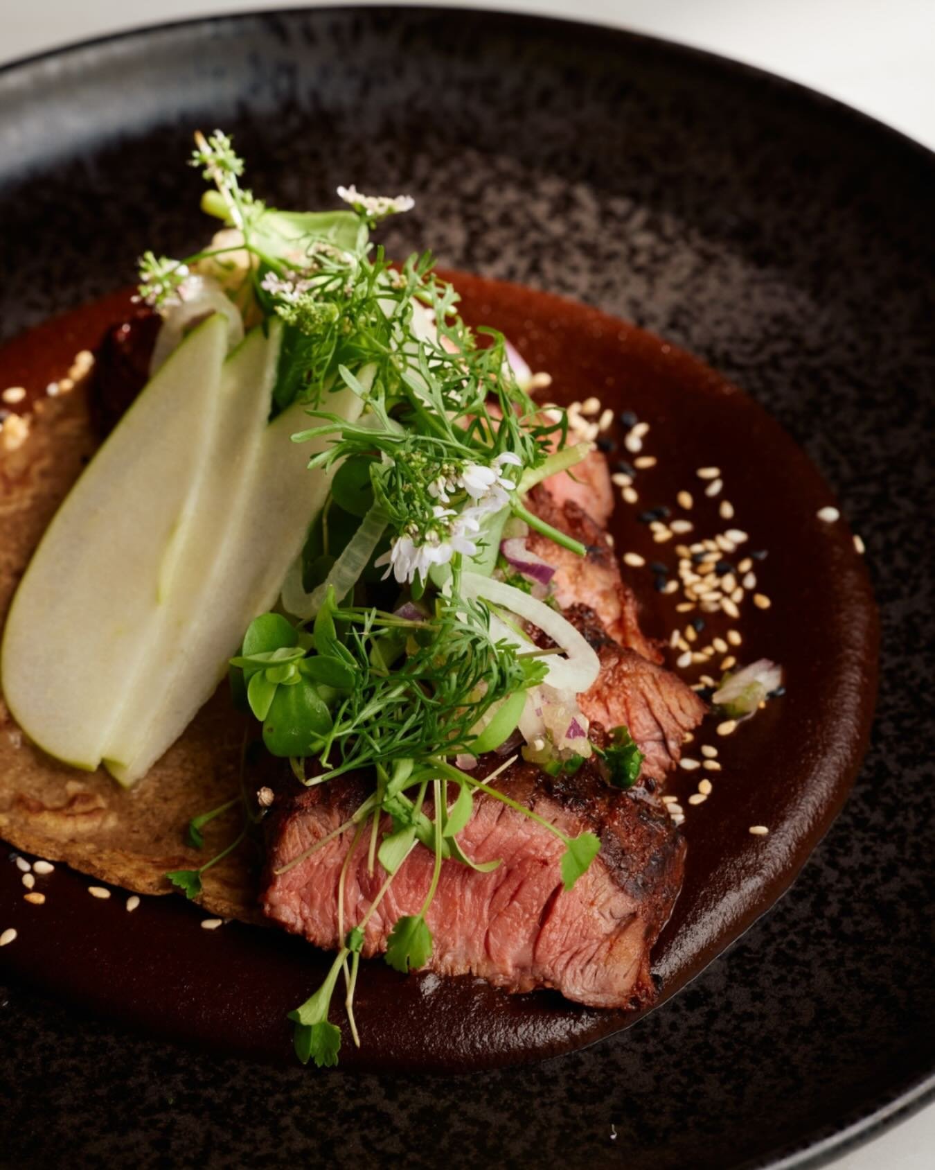 This Mole dish is layered, intentional, and deeply rooted in tradition.

Guajillo-marinated prime hanger steak is paired with a plantain tortilla and bright tomatillo pico de gallo, while slices of green apple add a crisp lift.

At the center is our 