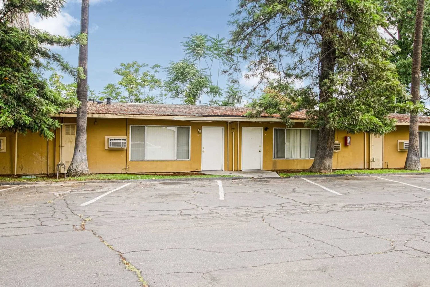 This image focuses directly on a section of the single-story building, showing two white front doors and large windows facing an open parking lot.