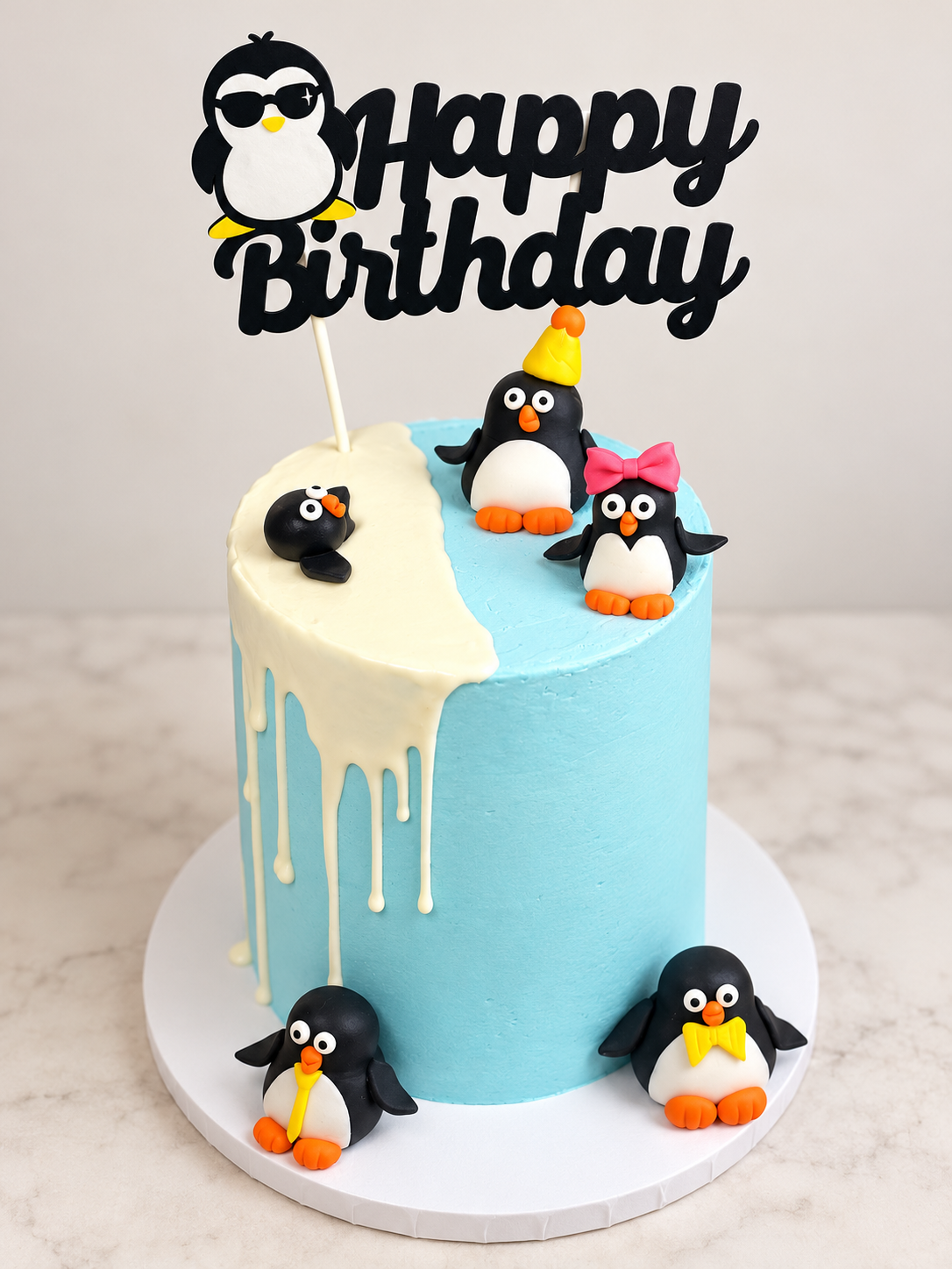 Light blue birthday cake with penguins and Happy Birthday topper