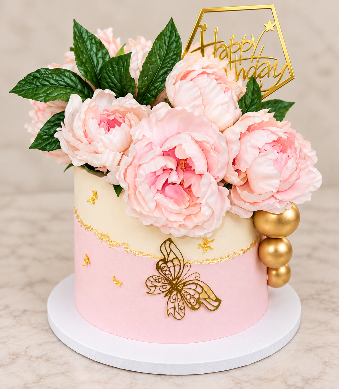 Elegant pink and tan celebration cake with blush pink flowers, greenery and gold accents