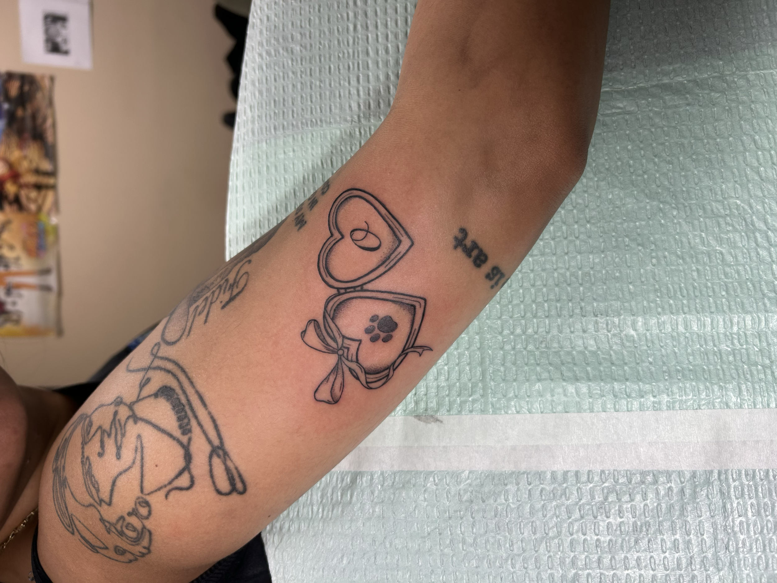 Tattooed arm with a bandage, tattoos include floating pizza slices with sprinkles, a heart, and fish.