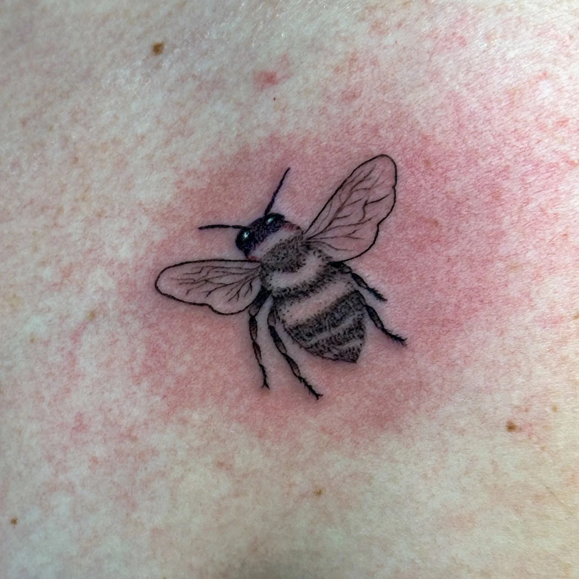 Tattoo of a bee on skin.