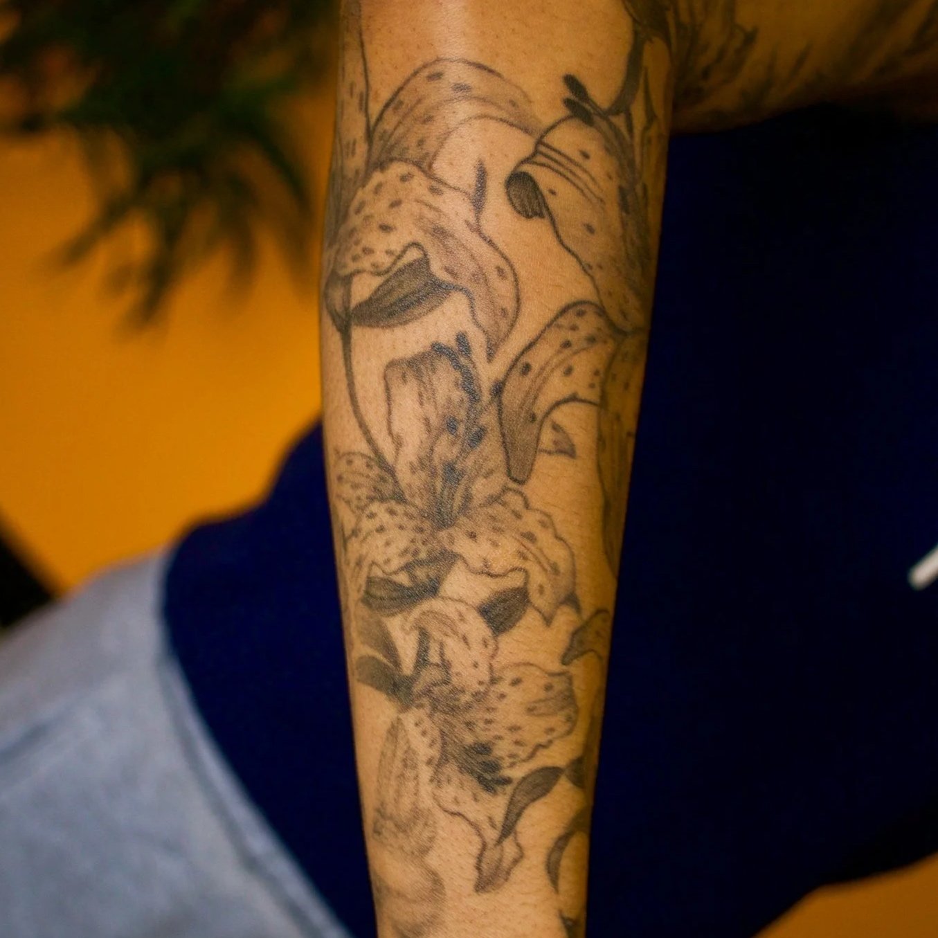 Black line tattoo of a lion's face on person's arm.